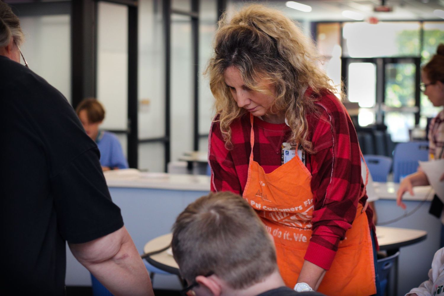 Students and instructors work together at tables in a bright classroom setting during an educational activity.