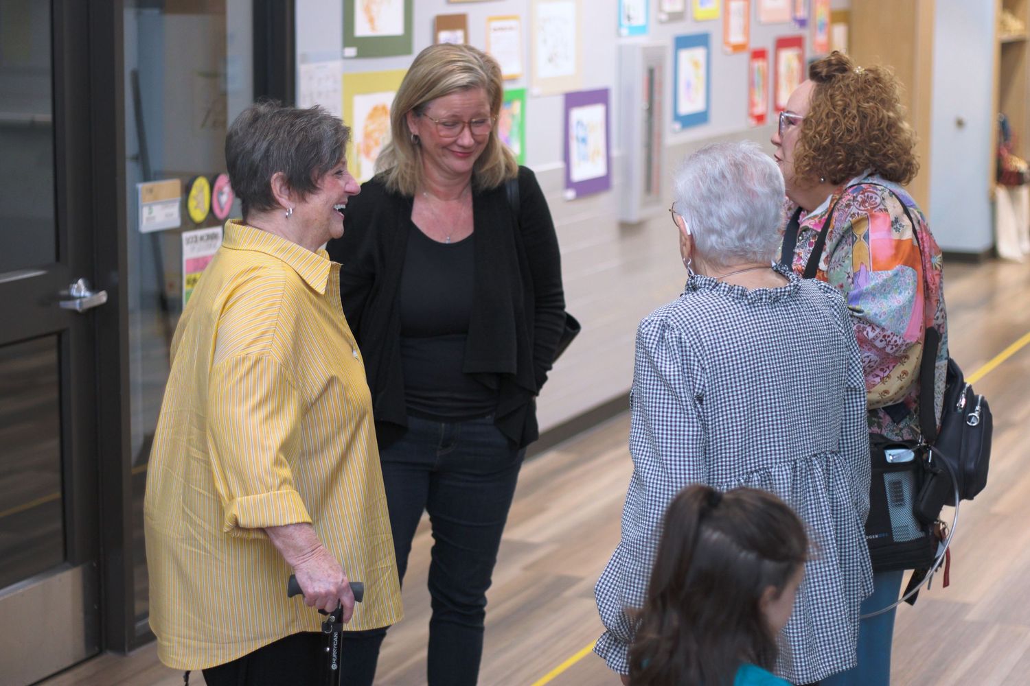People walking and interacting in a hallway with artwork displayed on the walls.