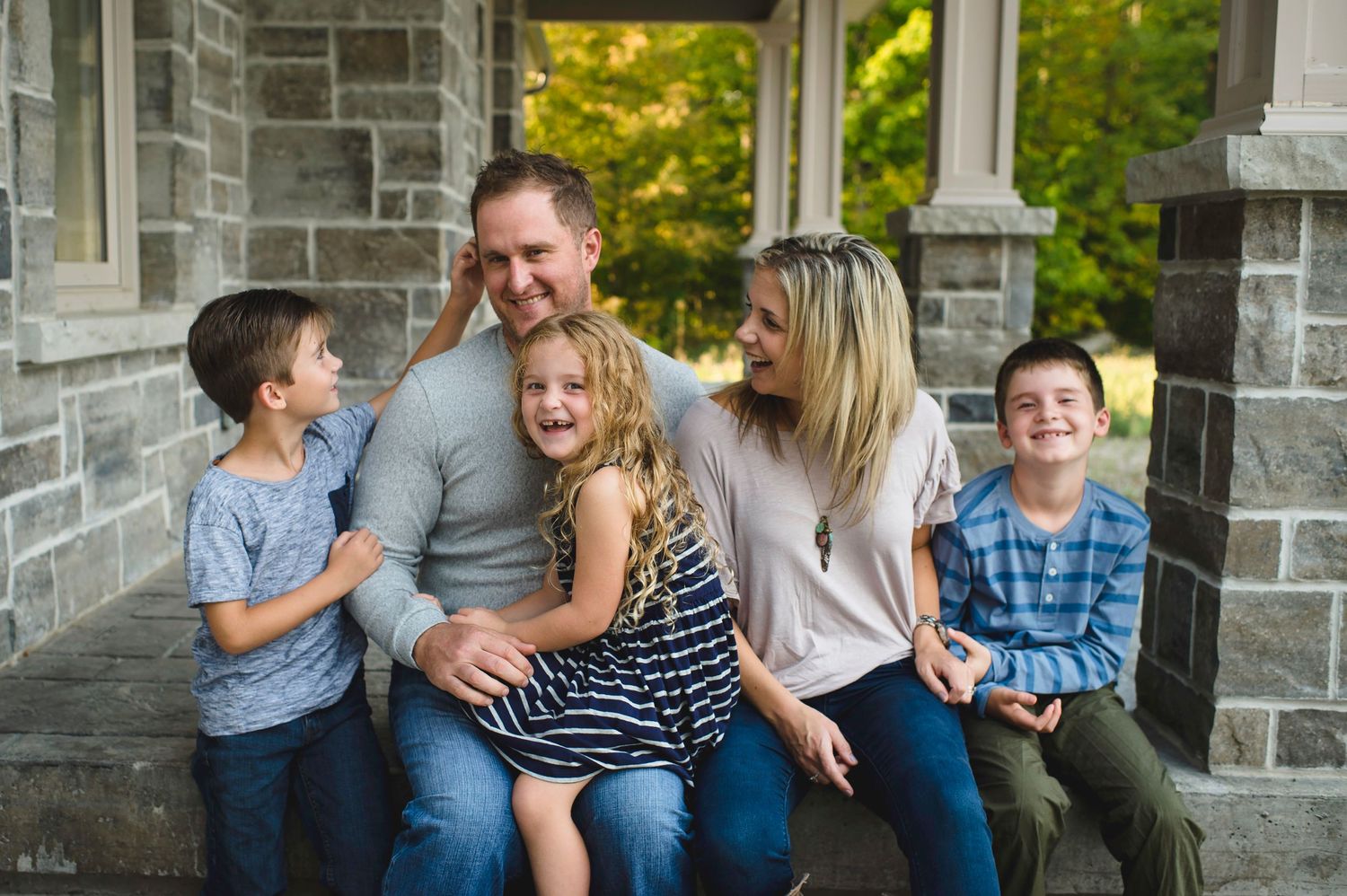 A happy family shares joyful moments together while sitting on stone steps outdoors.