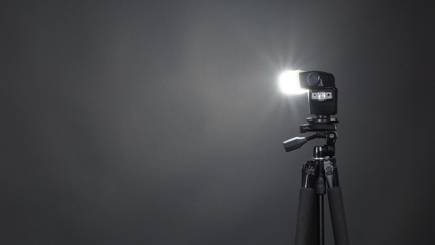 Professional studio lighting equipment and camera gear arranged in a dark room with dramatic shadows.