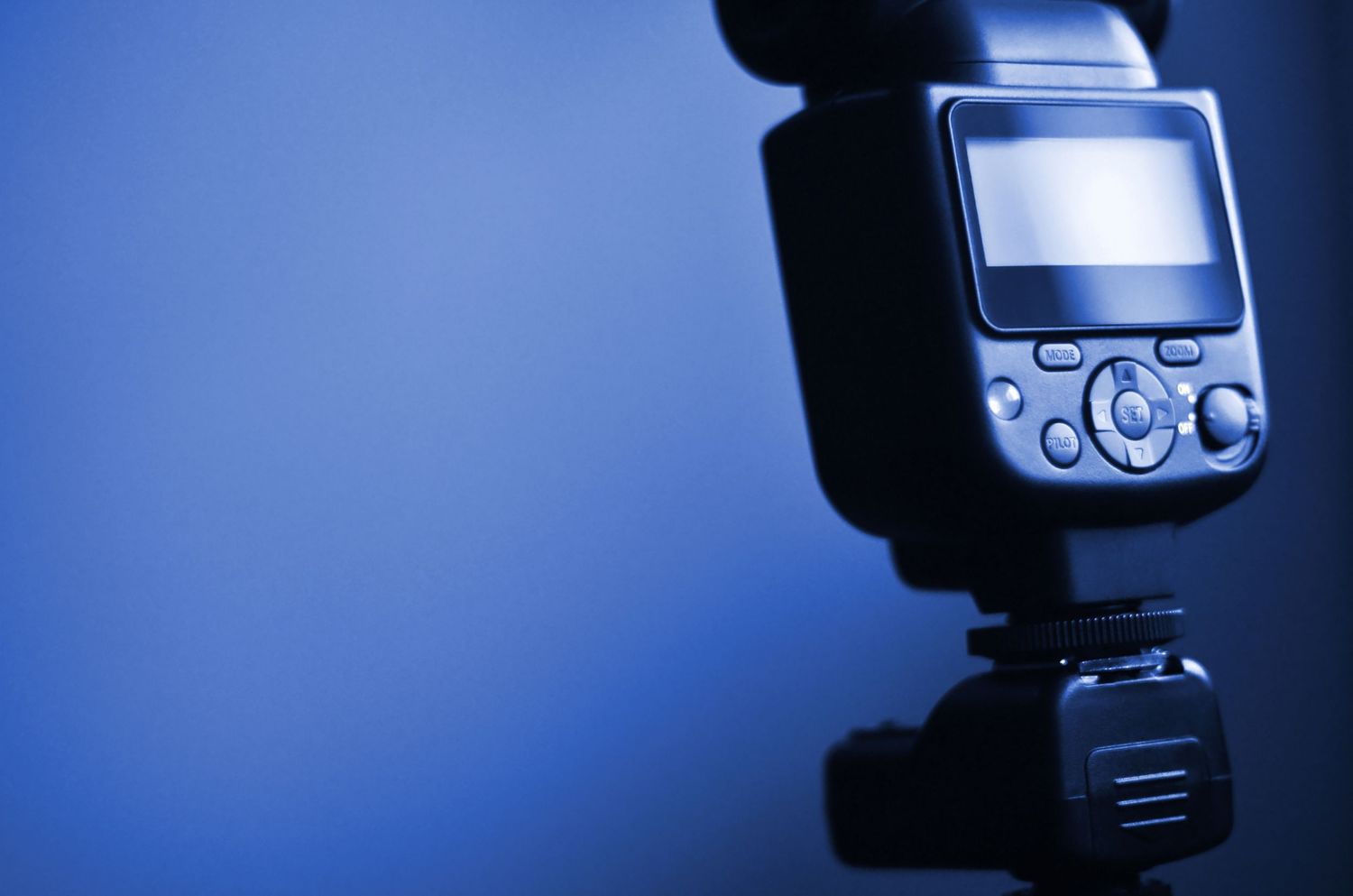 Professional camera equipment including flash units and speedlights arranged against a dark blue background.