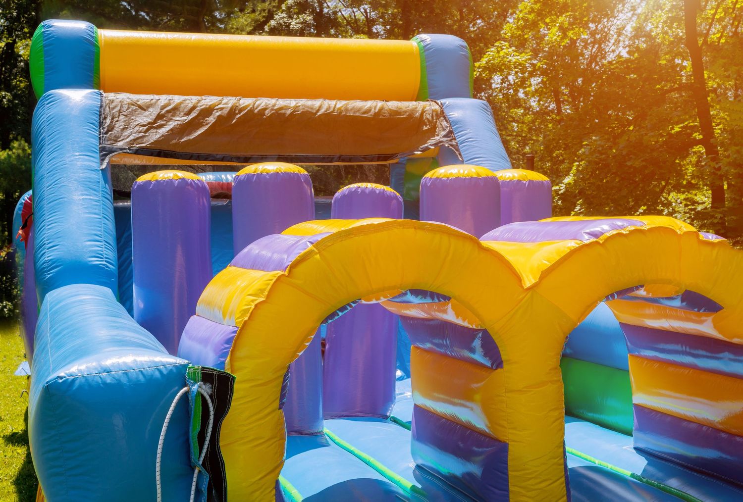 Colorful inflatable bounce house obstacle course with blue and yellow sections in sunlight.
