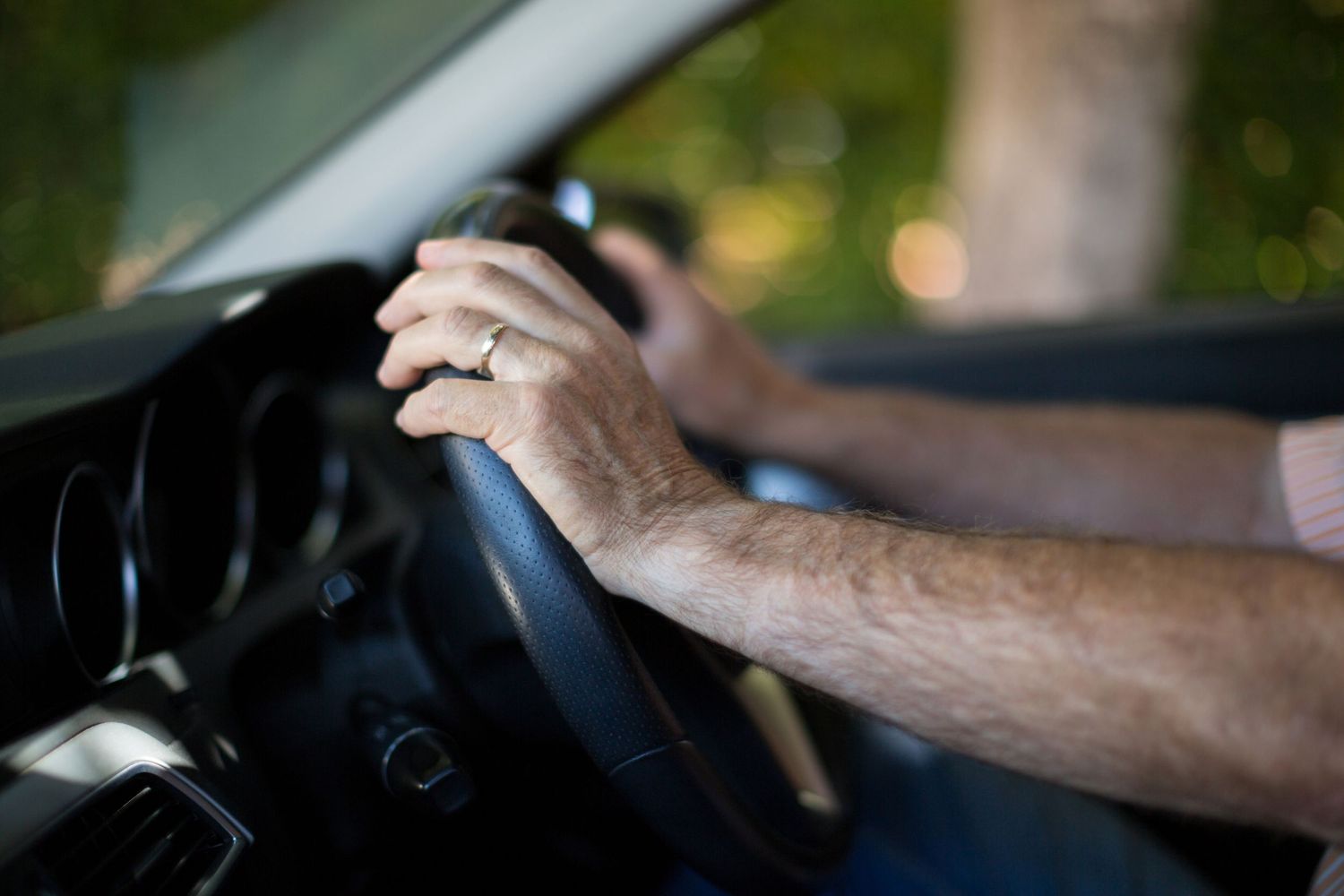 Close-up sequence of hands gripping and turning a car steering wheel while driving.