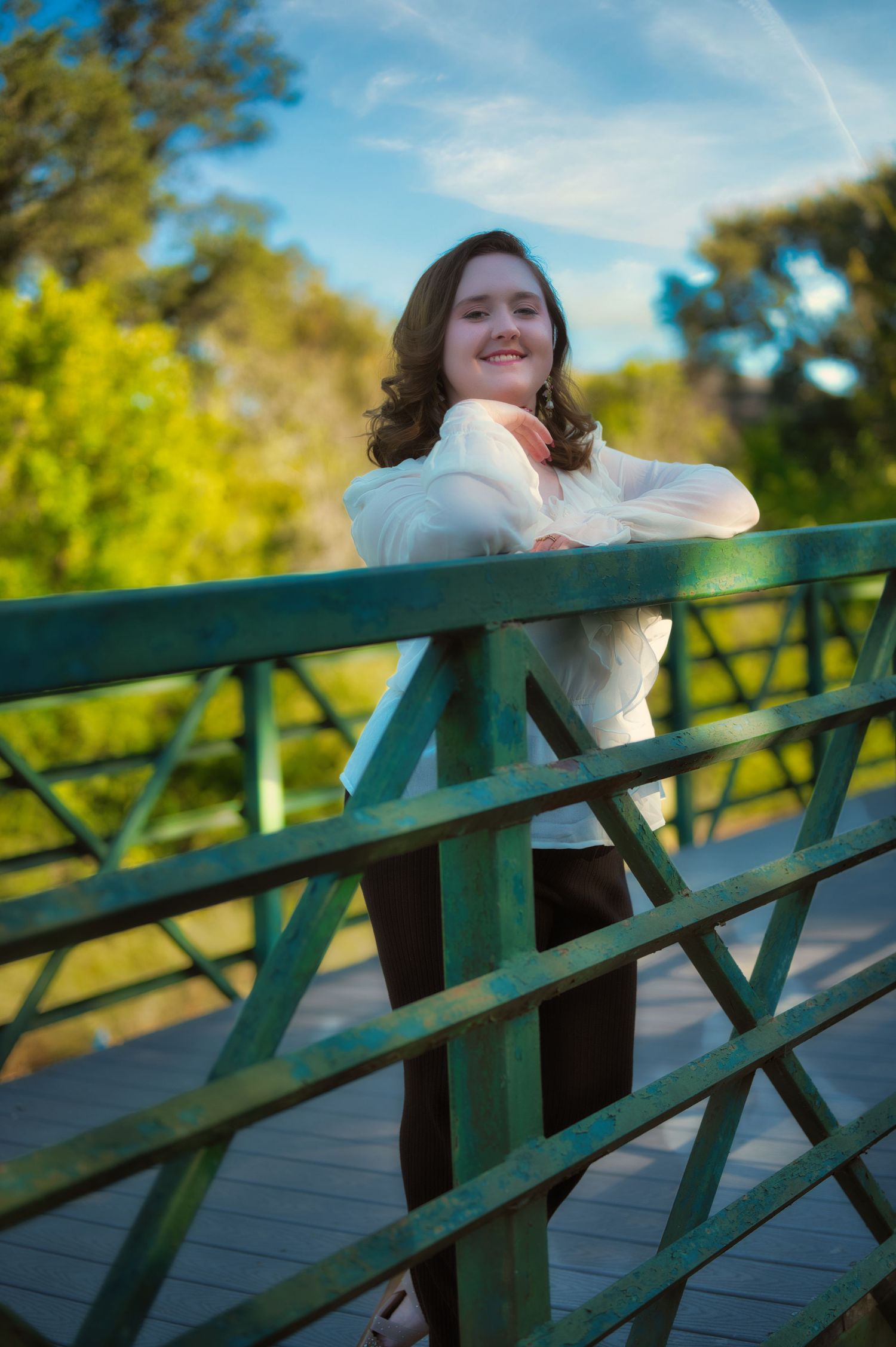 Photos showing someone leaning on a green railing against a bright blue sky and trees in the background. Azle family photo session.