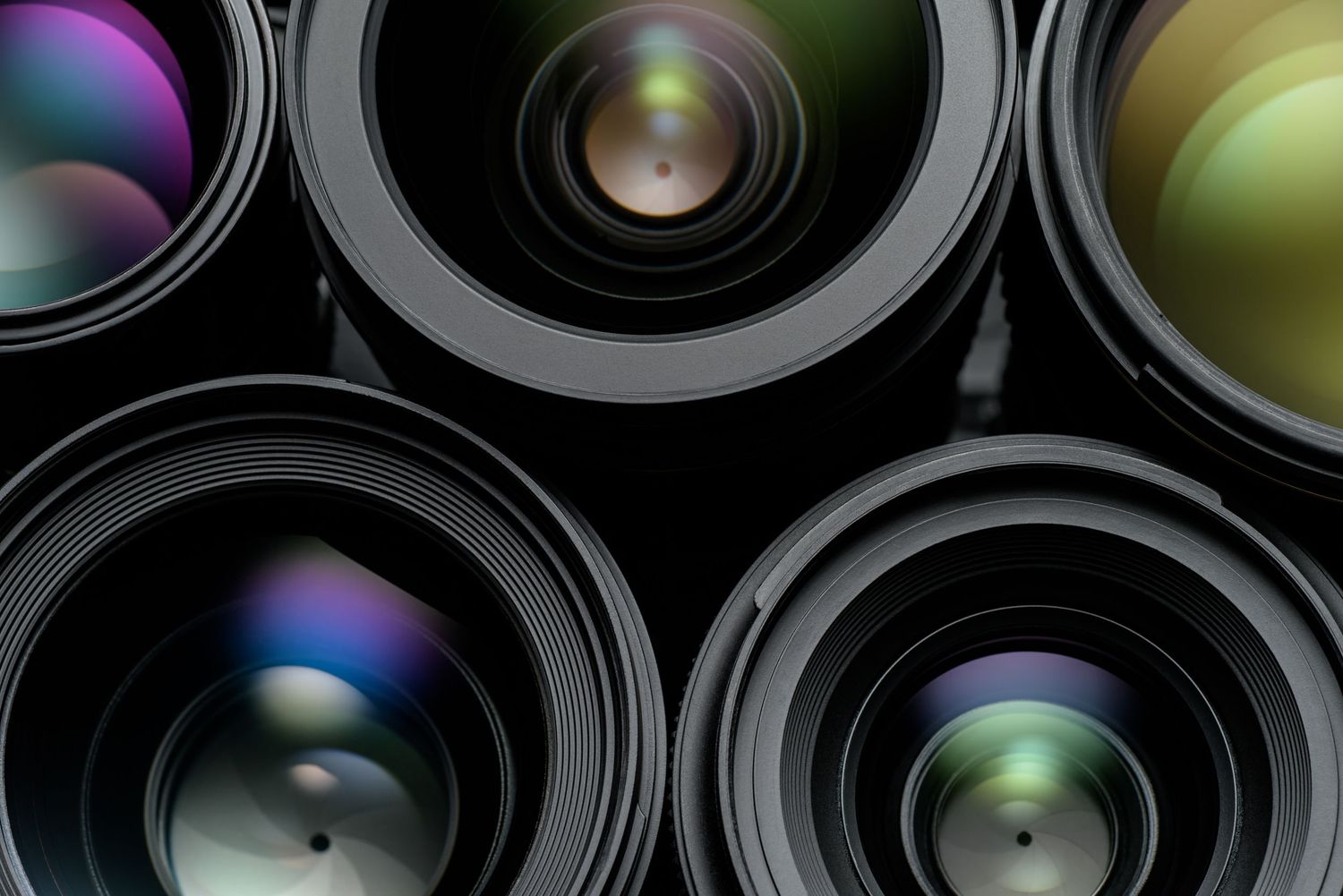 Abstract circular pattern of camera lenses arranged in a grid with colorful reflections and metallic surfaces.