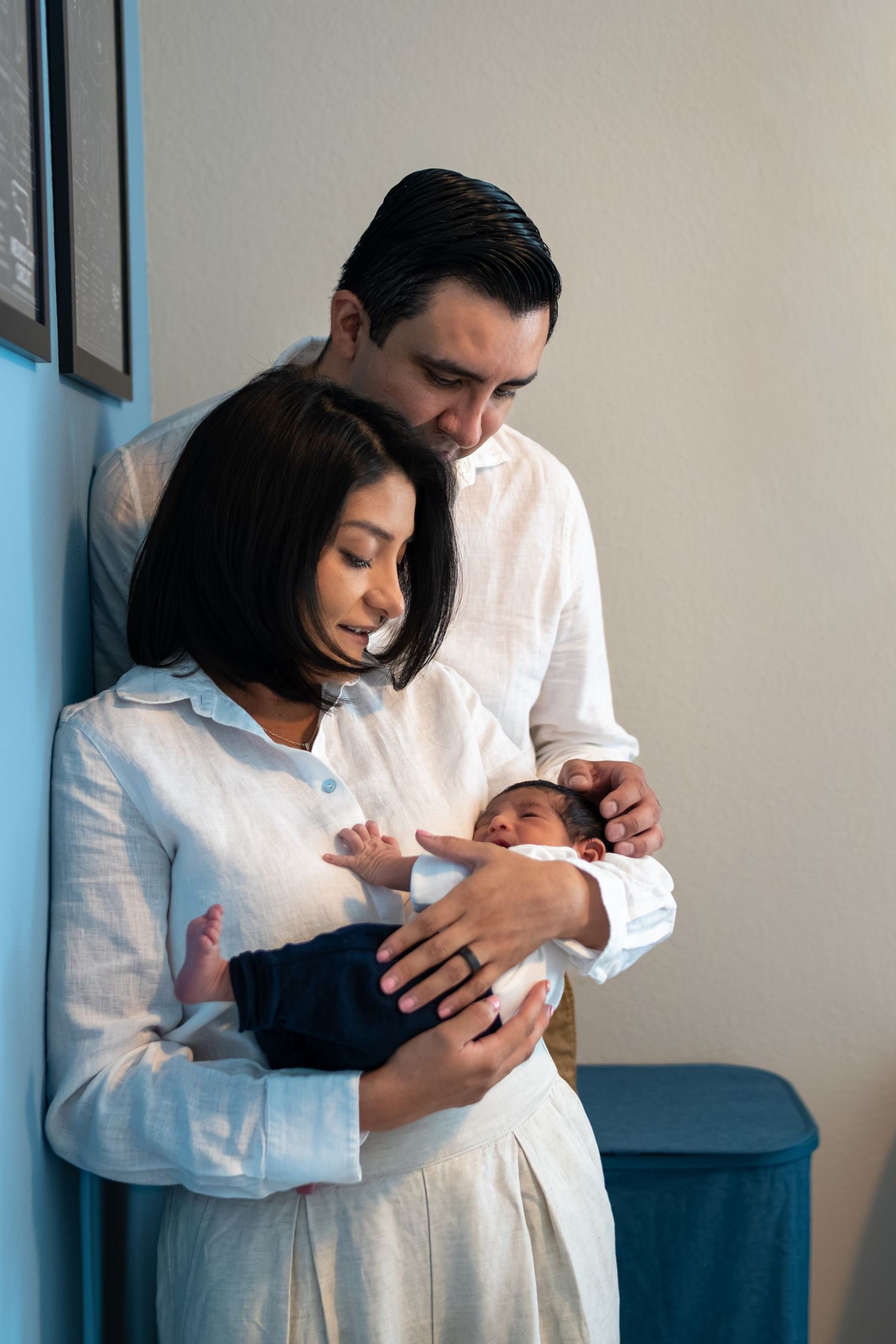 New parents lovingly gaze at their newborn baby, mother cradling infant while father looks on tenderly.