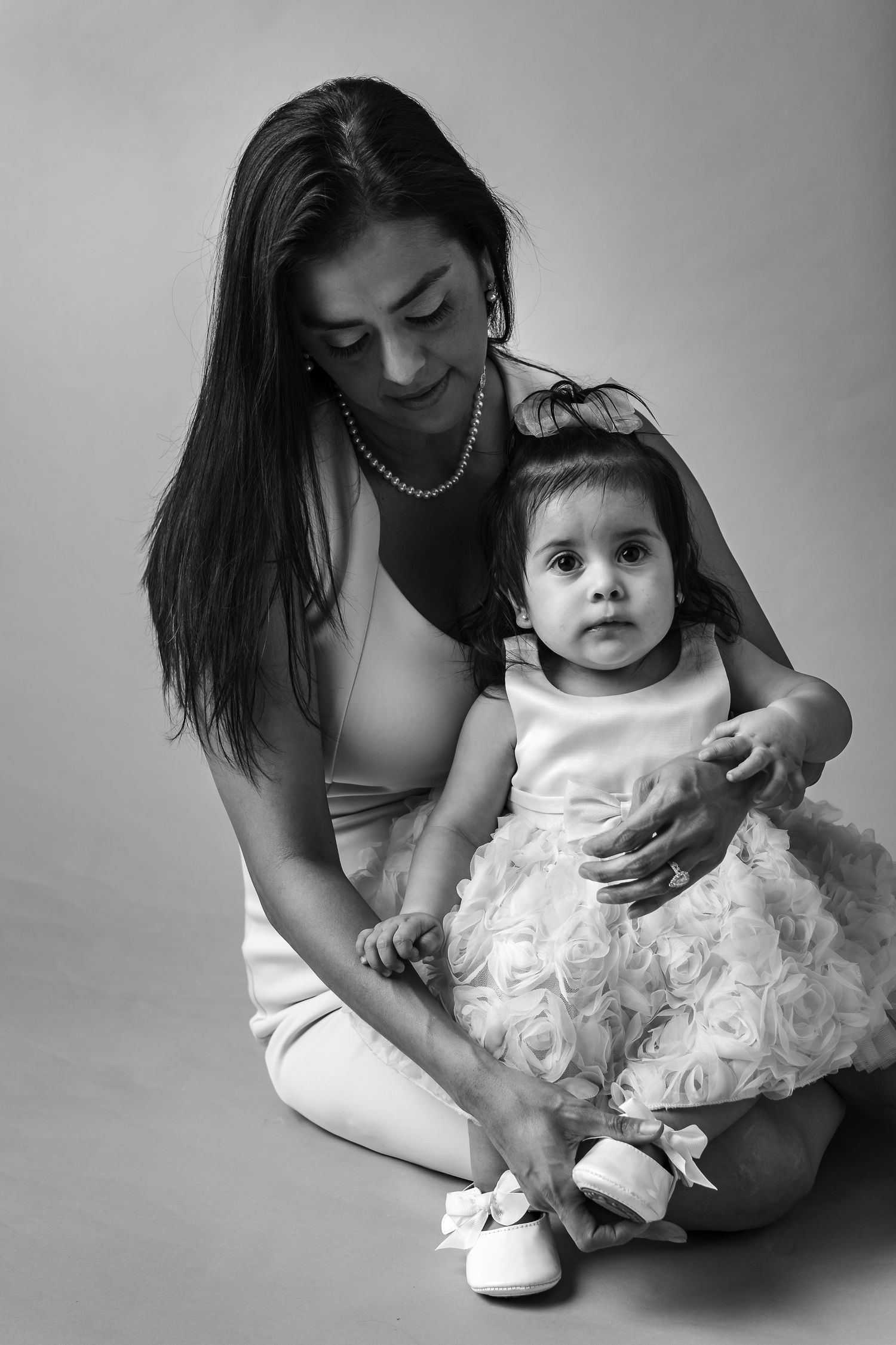 Black and white photos showing tender moments between parent and child in white outfits.