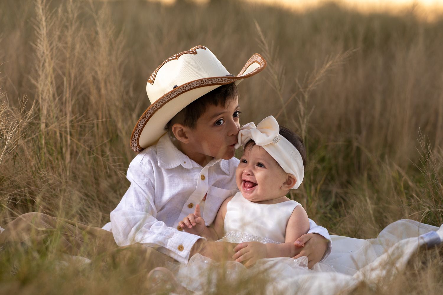 Children in white clothing laughing together in a golden field.