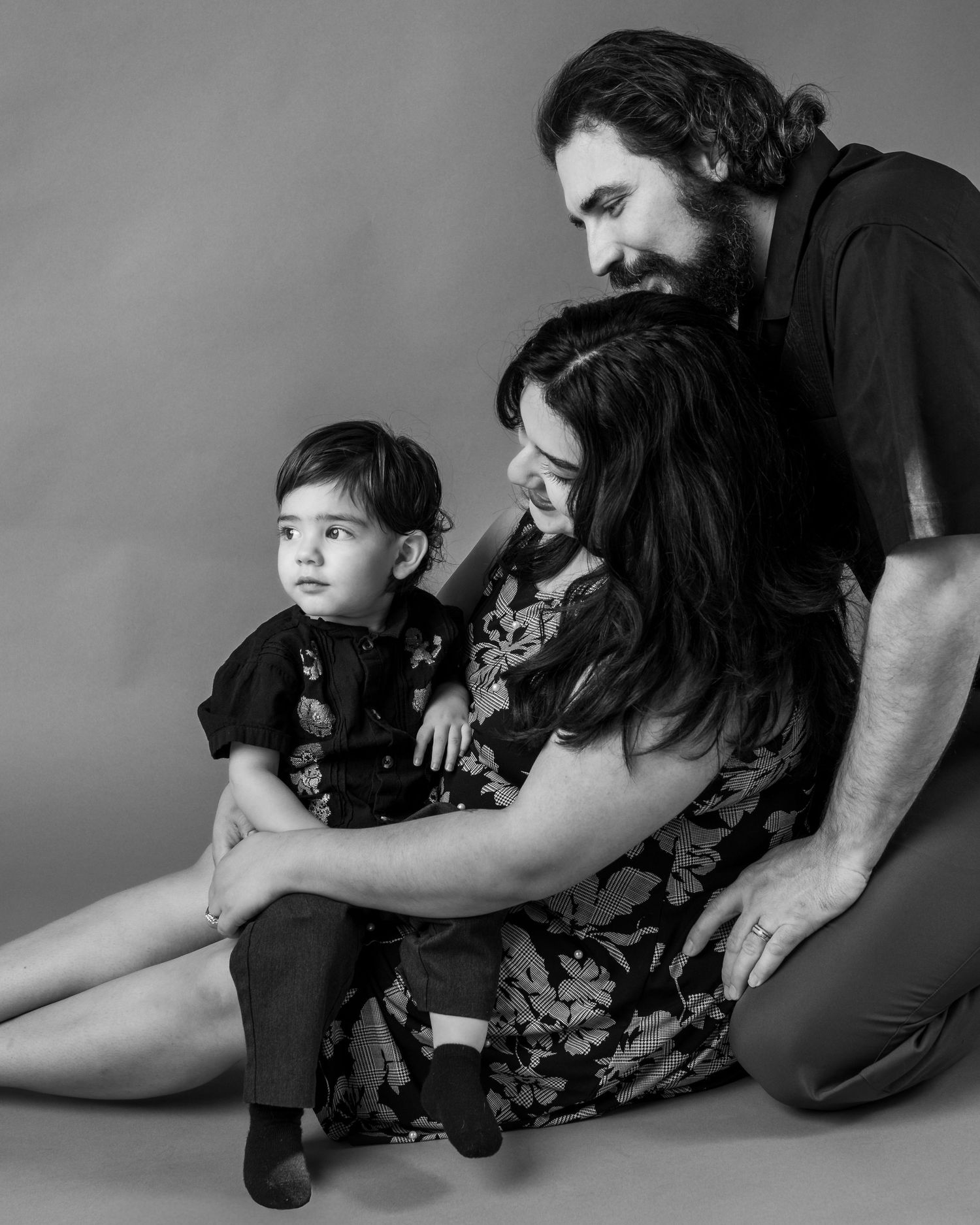 A series of black and white photos showing tender moments between a parent and child lying on the floor.