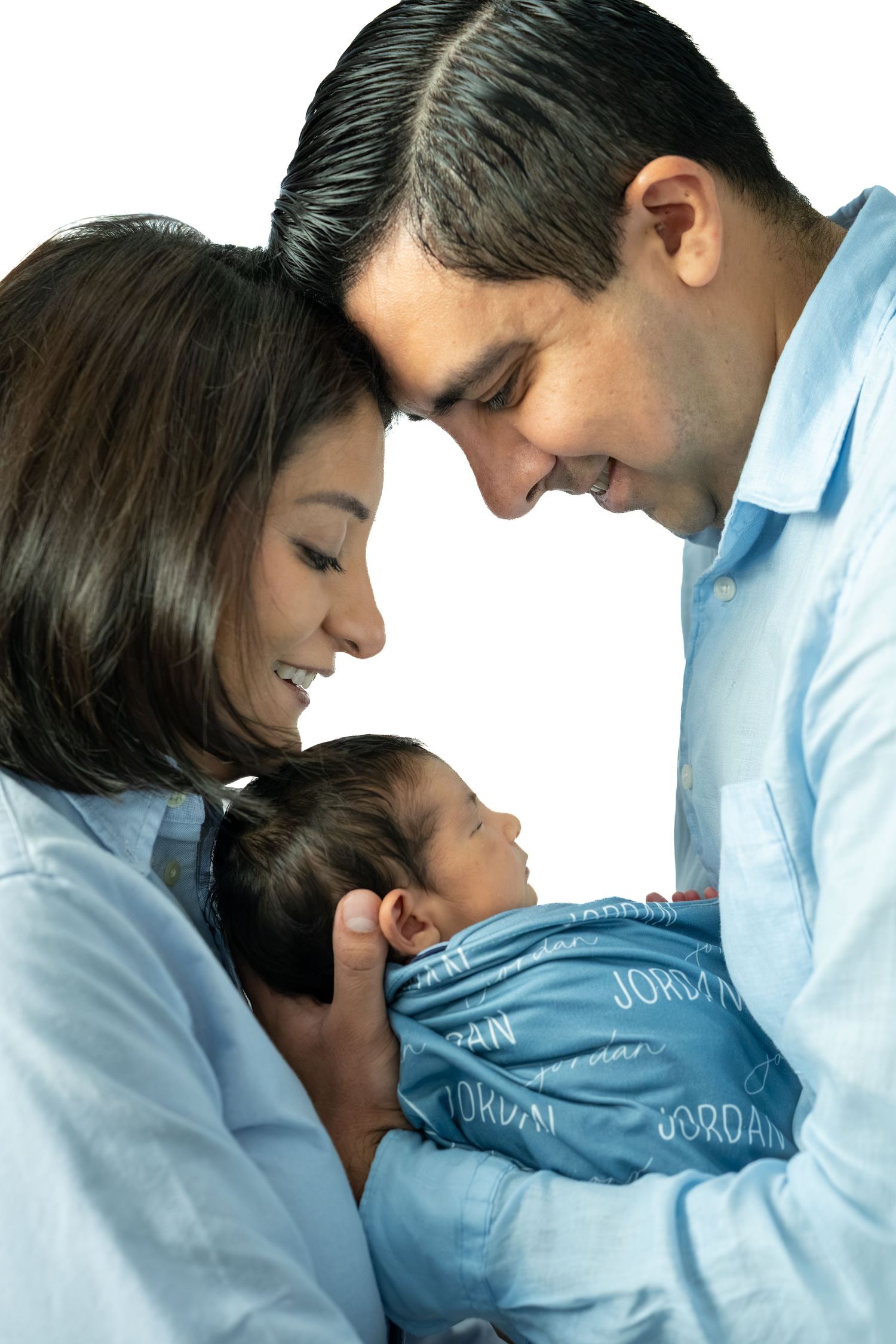 Smiling parents in blue shirts lovingly cradle their newborn baby dressed in a Jordan onesie.