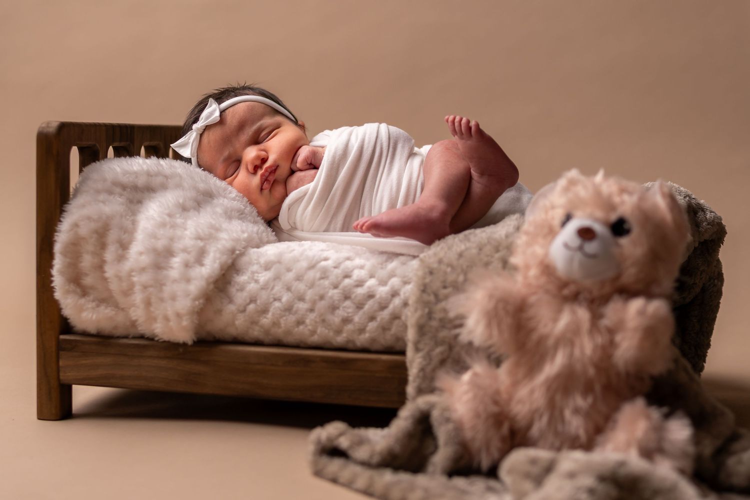 Series of cozy newborn photos on soft blankets in warm neutral tones.