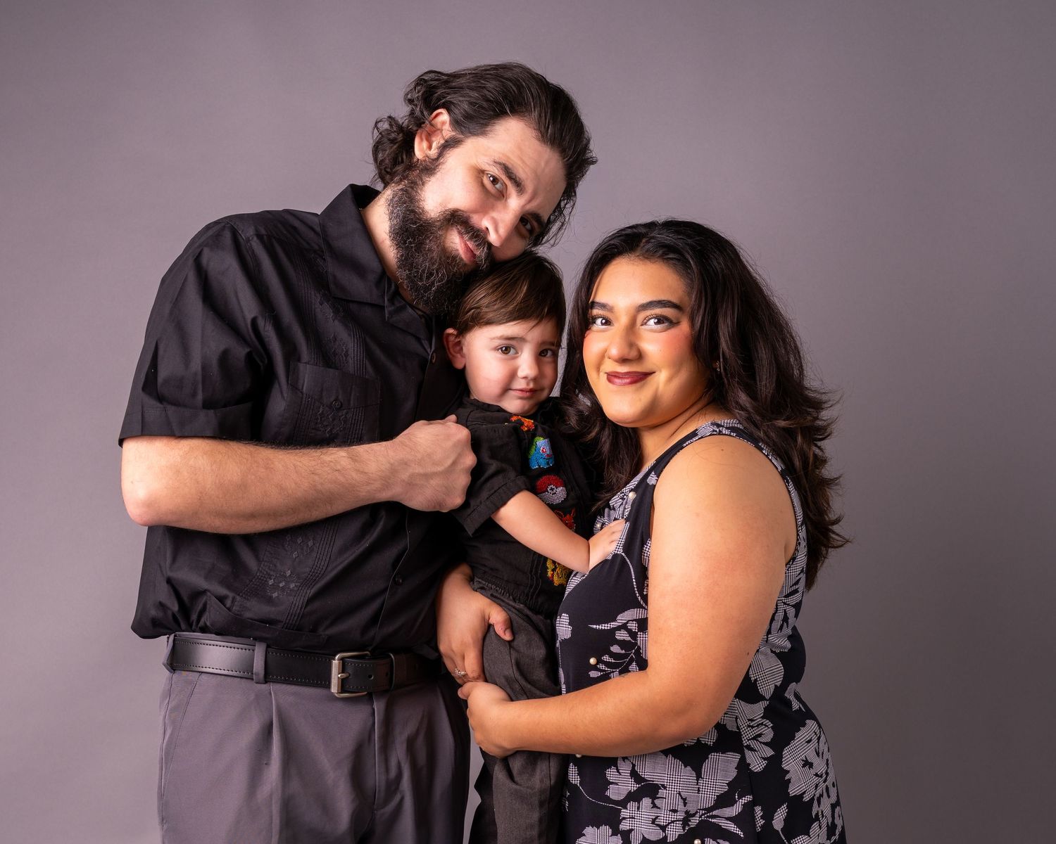 A couple in coordinated black and gray outfits pose together in a romantic photo series against a neutral backdrop.