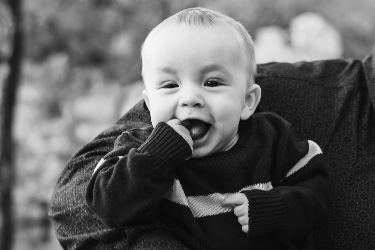 A black and white photo collage shows a baby laughing and making different joyful expressions.