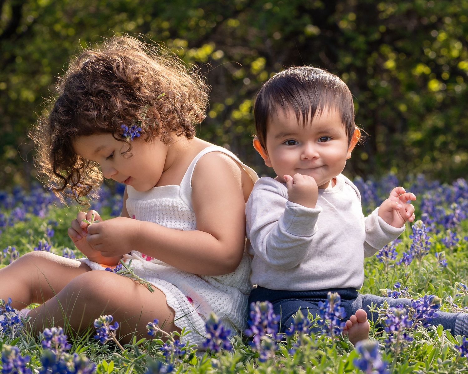 Children play and explore among vibrant purple bluebonnets blooming in a sunny spring meadow.