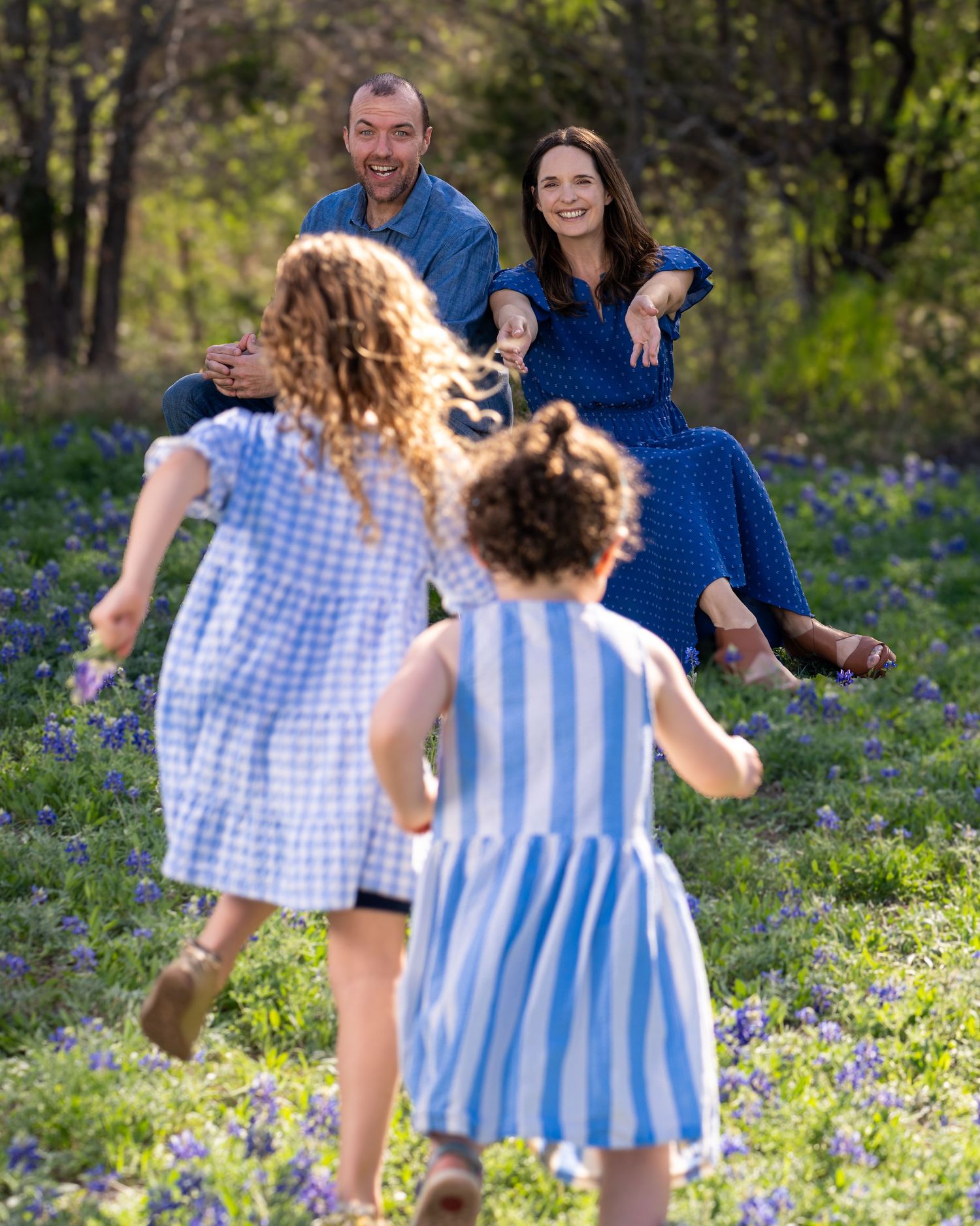 Family enjoying a spring day together in a field of blooming bluebonnets.