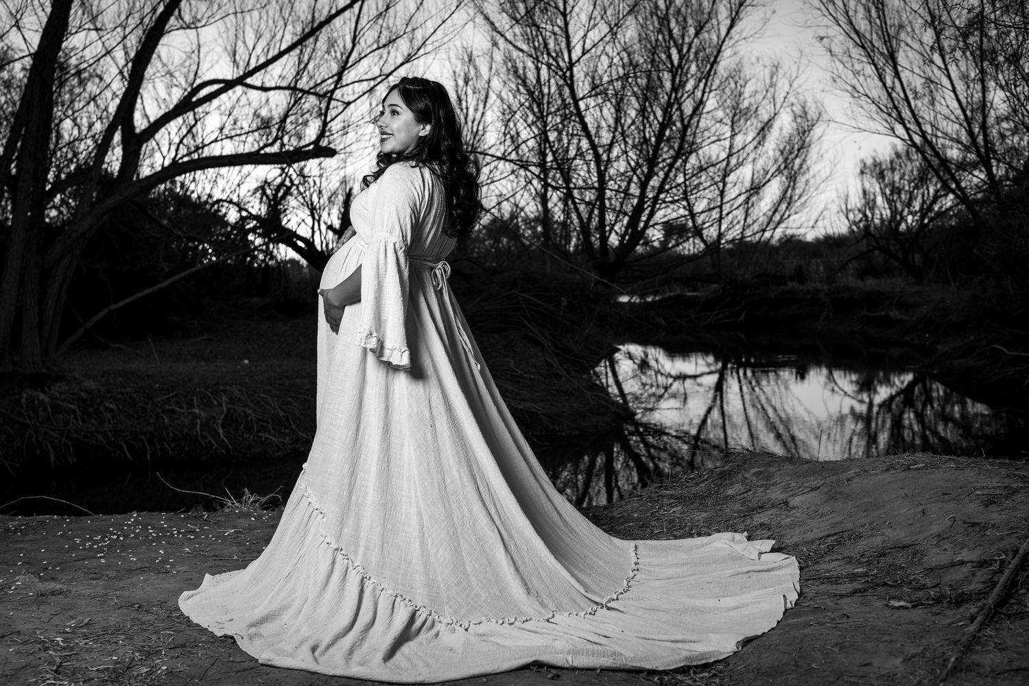 Black and white wedding dress photos showing a flowing train in a natural outdoor setting against bare trees.