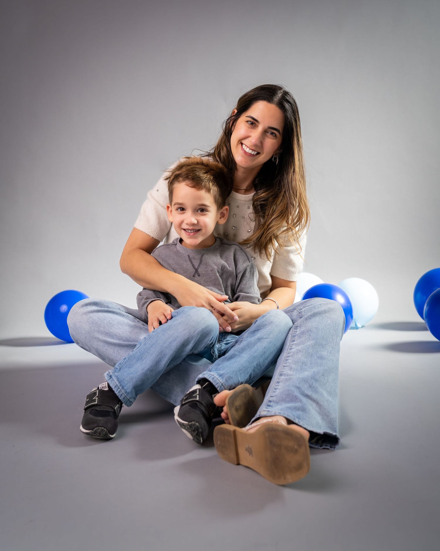 A sequence of playful poses showing someone sitting and lying on a gray studio floor with blue lighting elements.