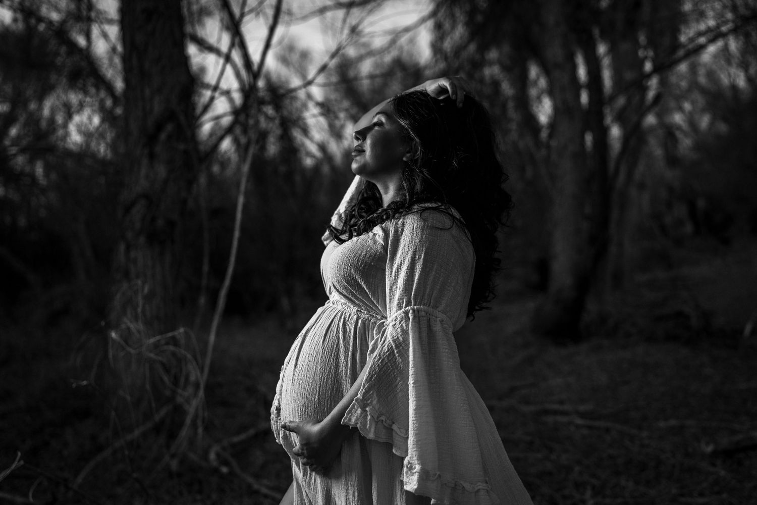 A black and white photo series shows a couple embracing in a wooded setting during a romantic outdoor photoshoot.