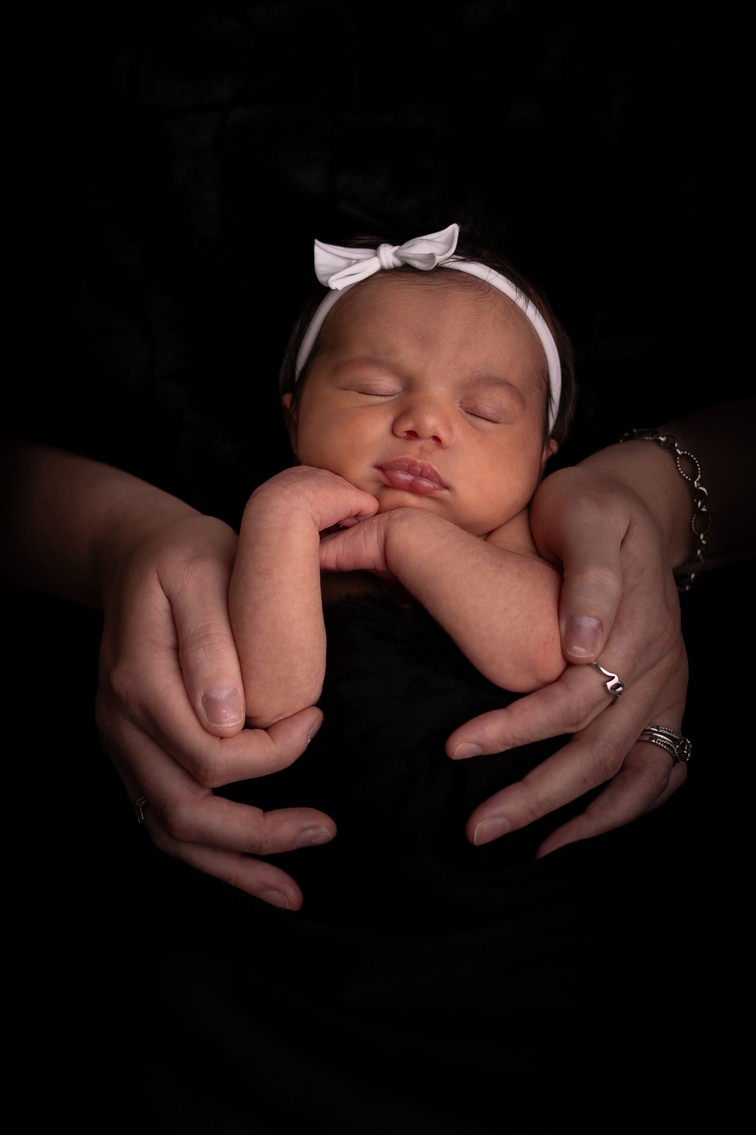 A series of artistic black and white photos showing tiny newborn hands being gently cradled by adult hands.