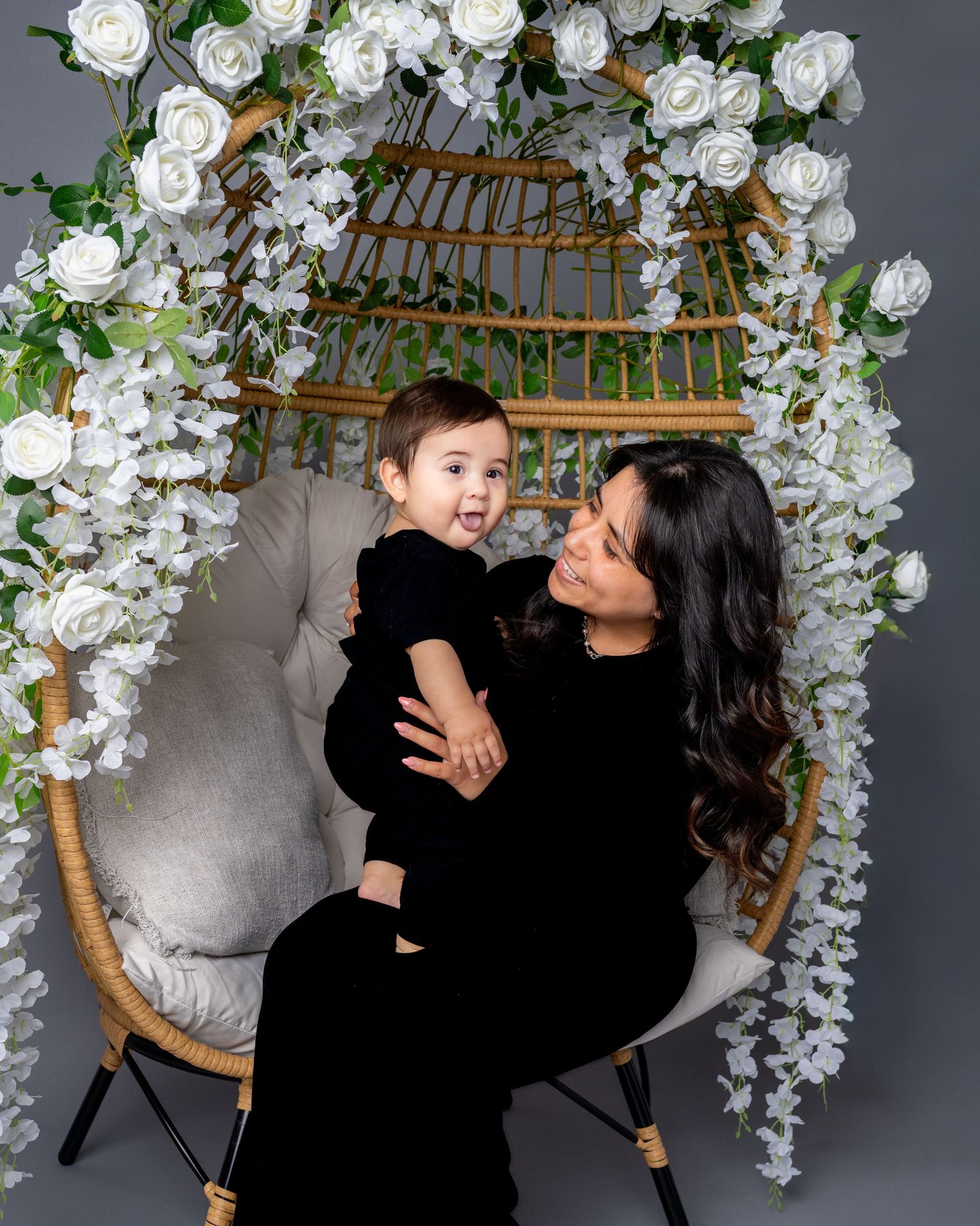 A tender moment shared between parent and child in a studio setting with white floral decorations and a wooden chair.
