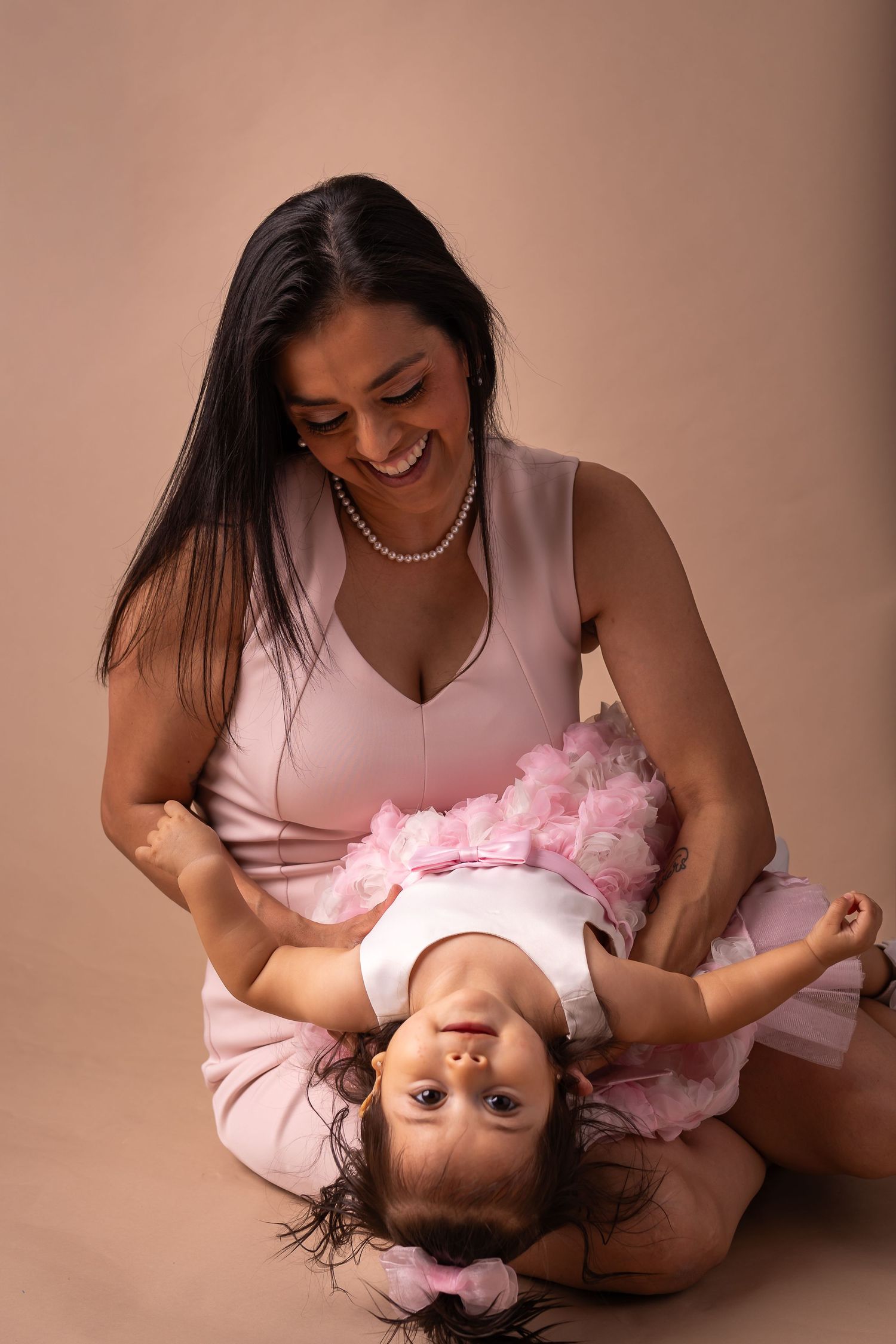 A series of connected photos showing a tender moment between parent and baby in soft pink lighting.
