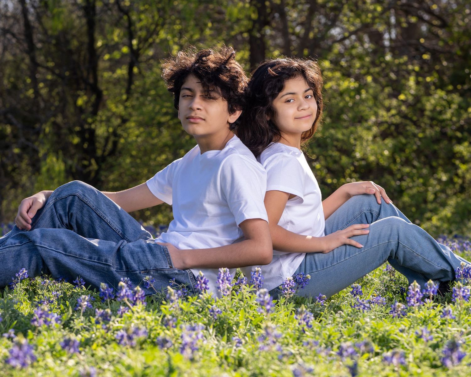 A couple relaxes together in a field of purple wildflowers on a sunny spring day.