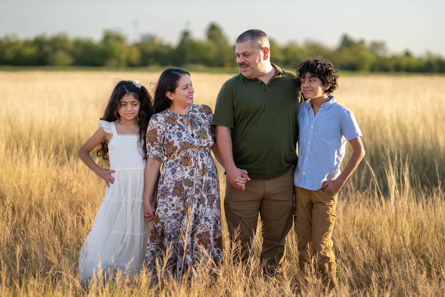 Family photo session in a serene field during sunset golden hour.