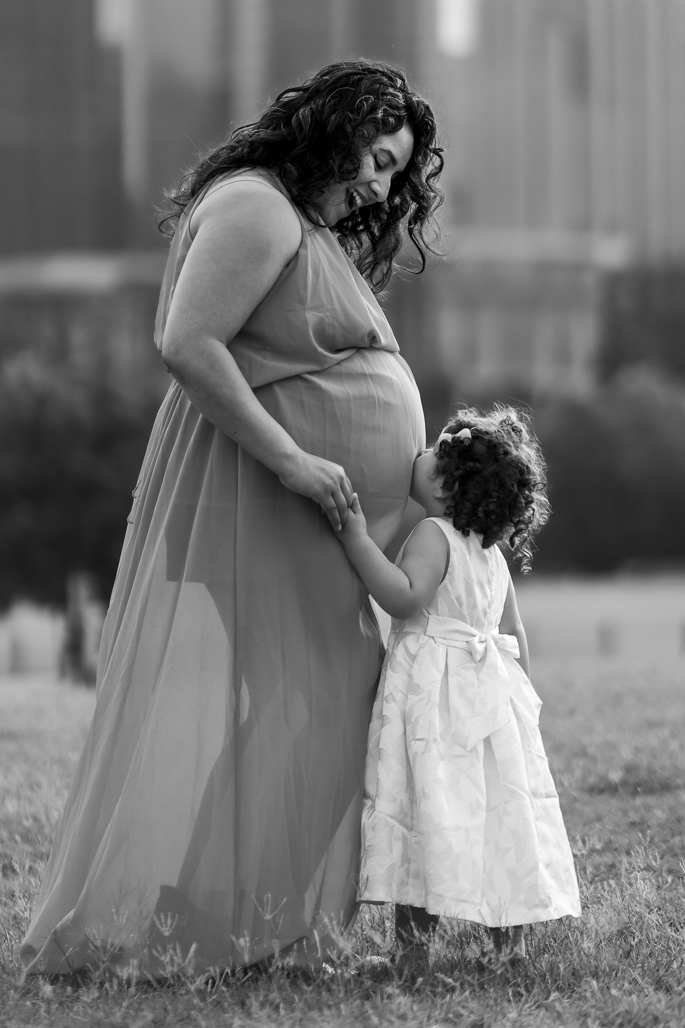 Maternity Photography: A tender moment captured in black and white of an expectant mother & toddler in Butler Park with Austin TX skyline.