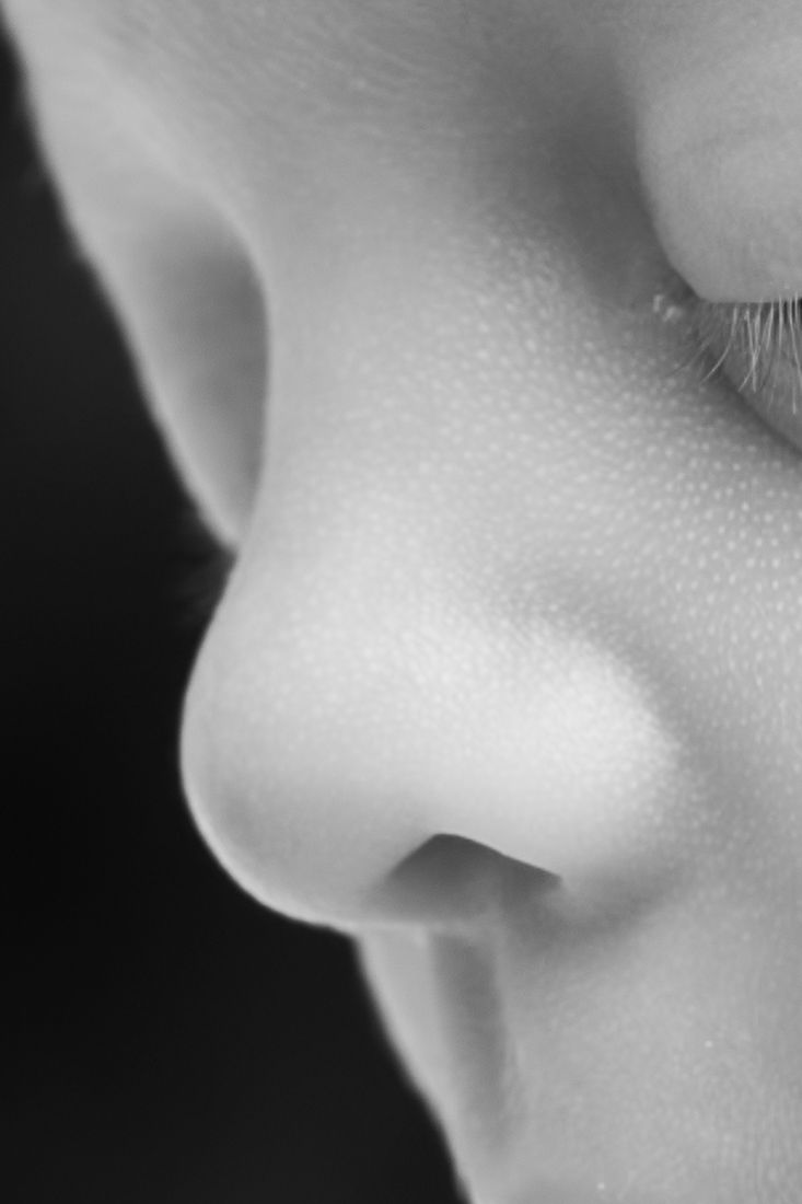 Close-up black and white portrait of a child's nose and cheek showing delicate skin texture and eyelashes.