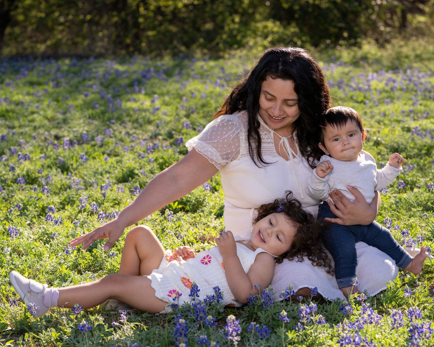 A family relaxes together in a field of blooming bluebonnets on a sunny spring day.