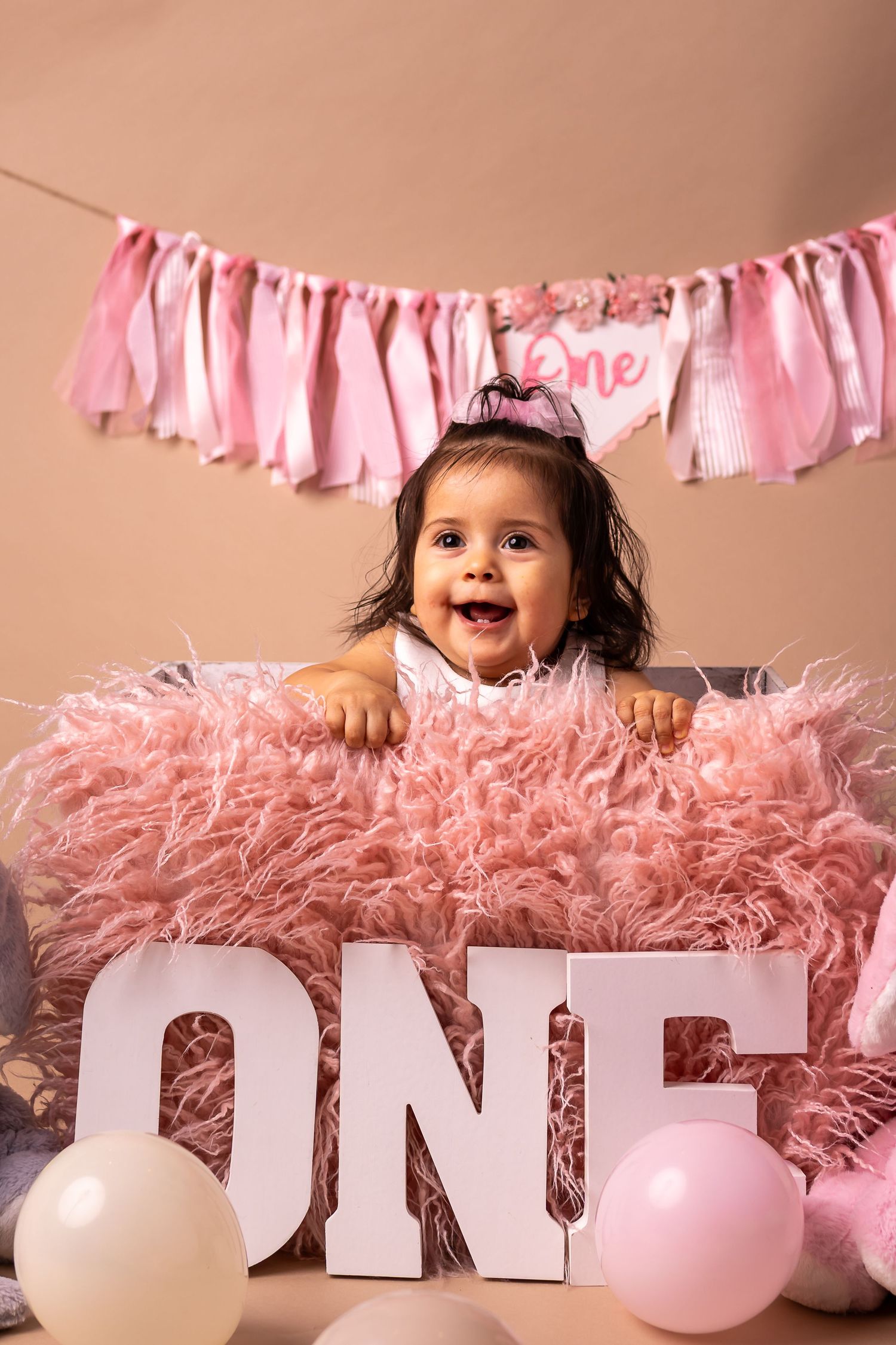 Pink birthday decorations with 'ONE' text and fluffy pink tulle create a festive first birthday backdrop.