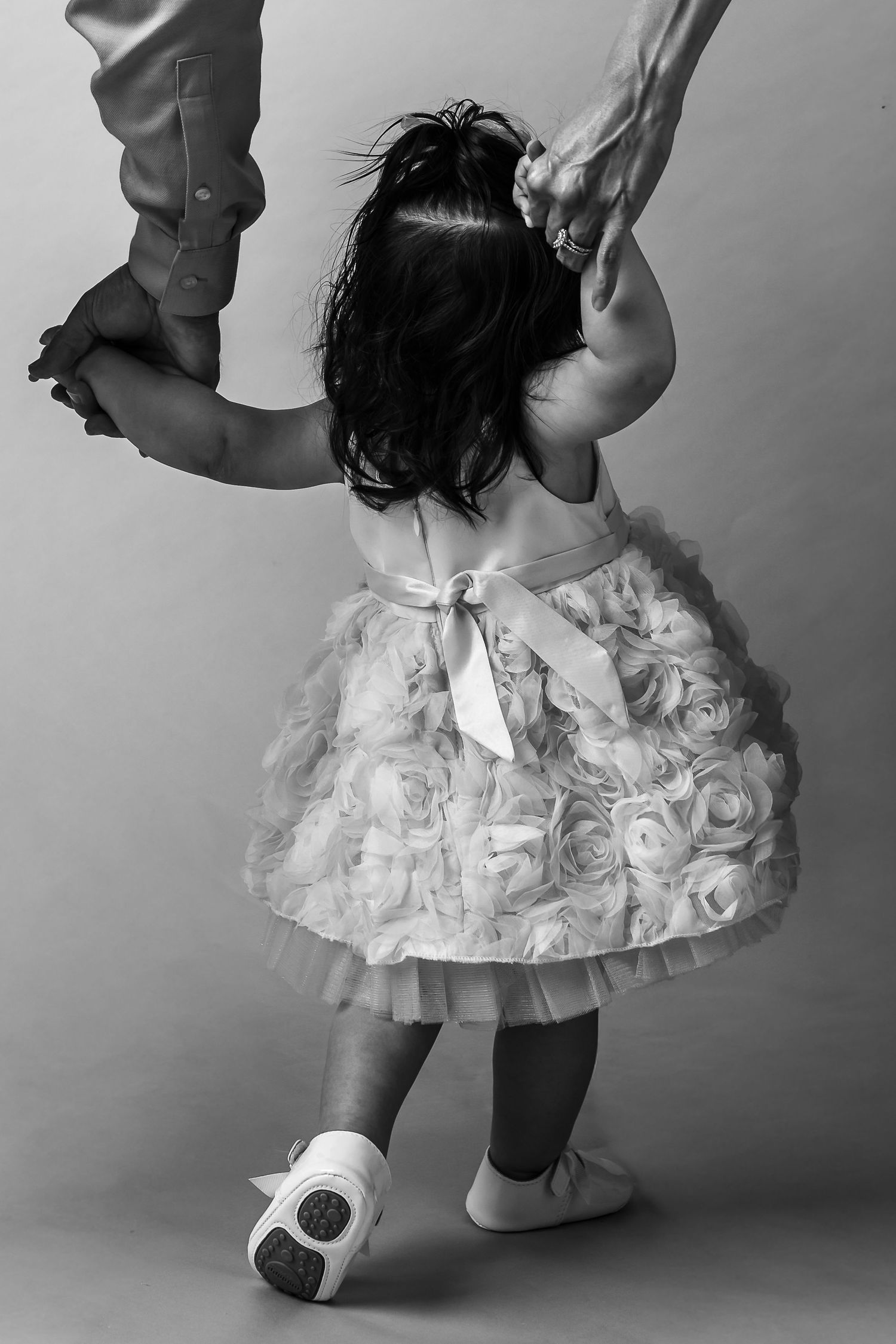 Black and white photo series showing close-up views of a small child wearing a white tutu dress and ballet shoes.
