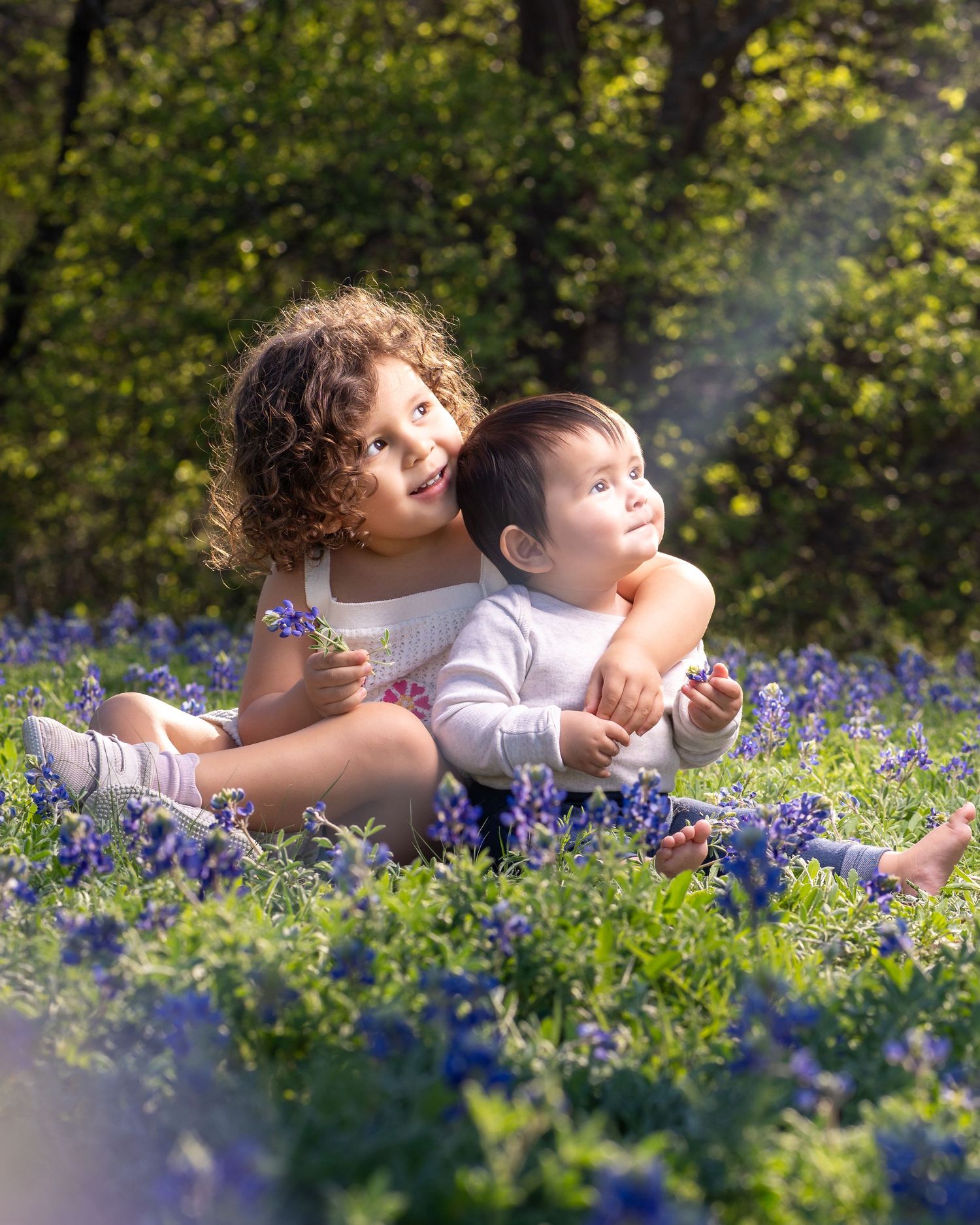 Two people lying in a field of blooming bluebonnets on a sunny spring day.