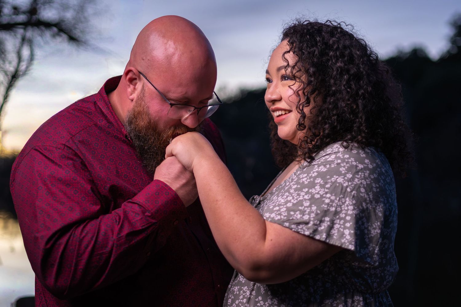 A romantic couple shares intimate moments in a series of outdoor engagement photos at sunset.