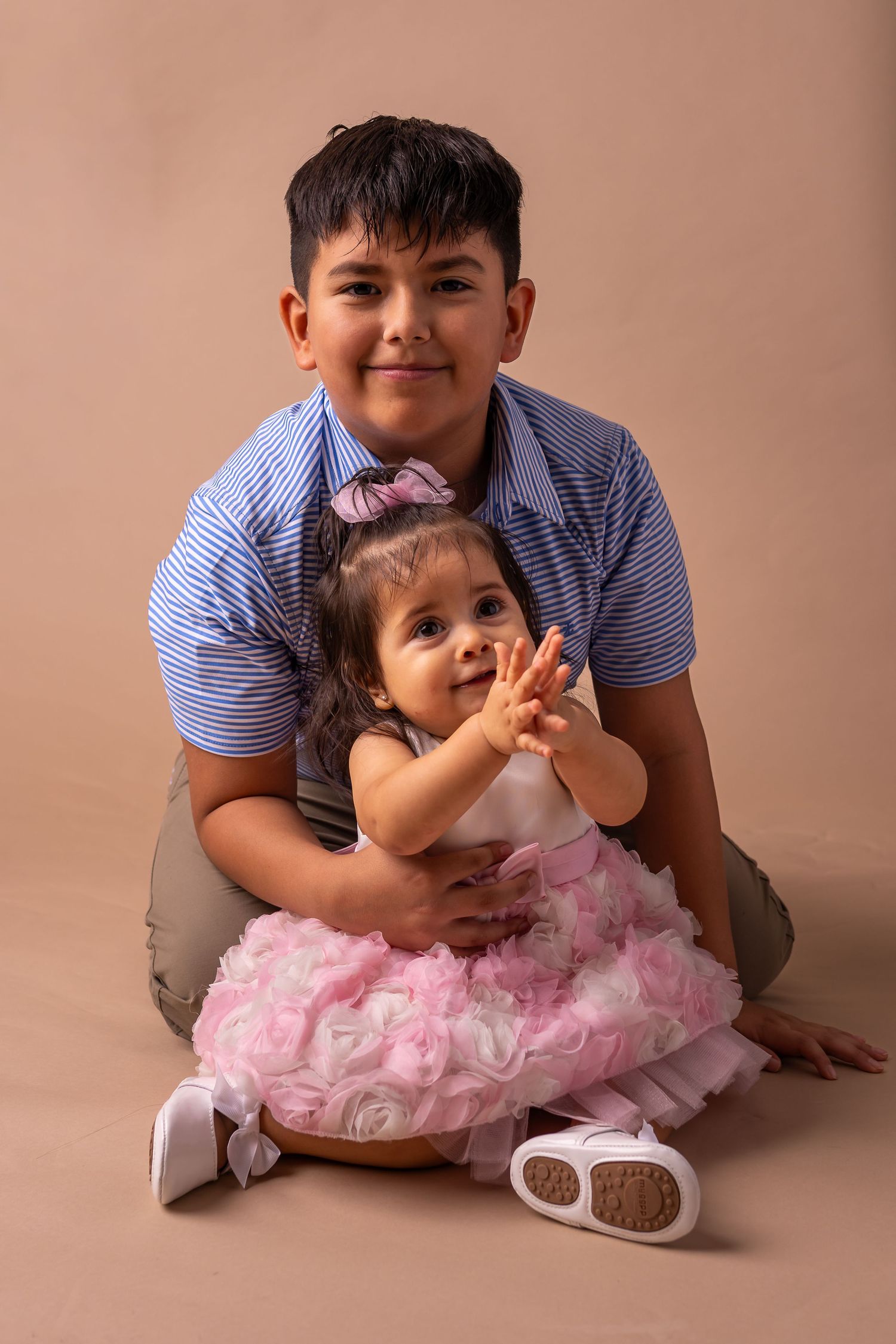 A series of photos showing a child in a pink tulle dress playing on a beige backdrop.