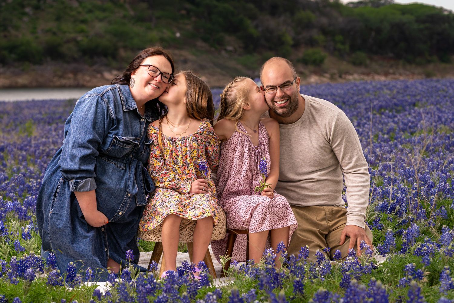 Family of four smiling together in a vibrant Texas bluebonnet field, capturing a joyful spring portrait.