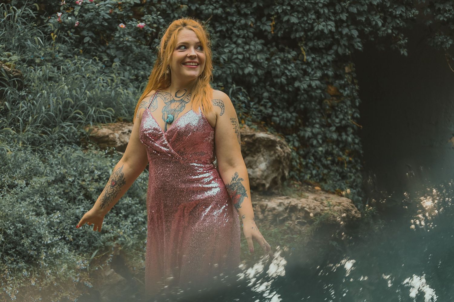 A person in a pink sequin dress twirls joyfully in a lush garden setting at dusk.