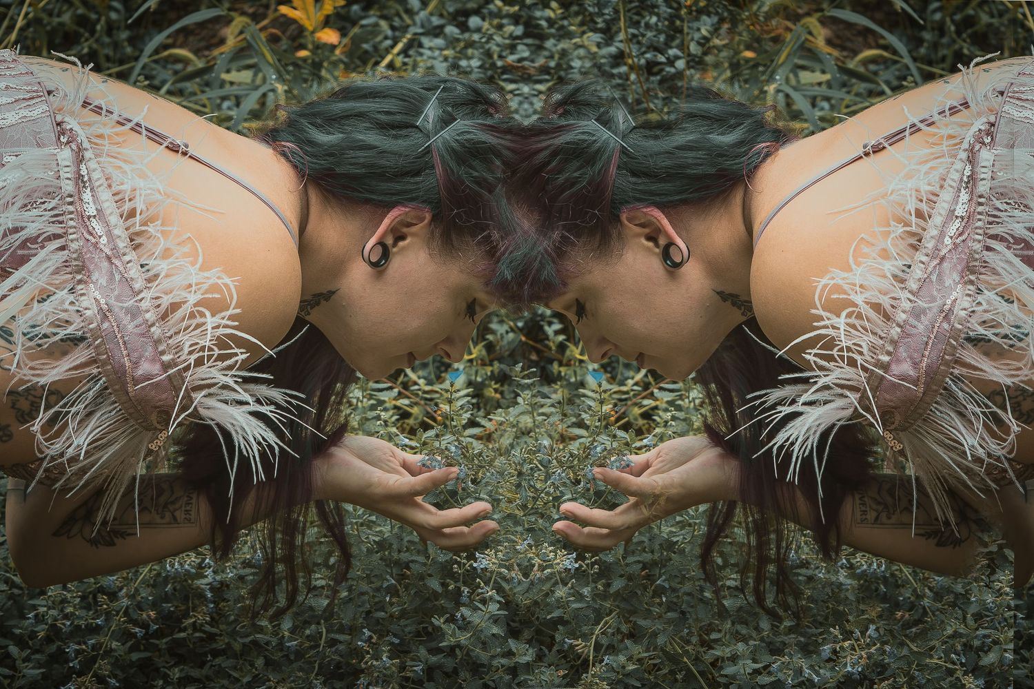 Mirrored artistic portrait of a figure in a feathered dress lying in green foliage, creating a symmetrical reflection.