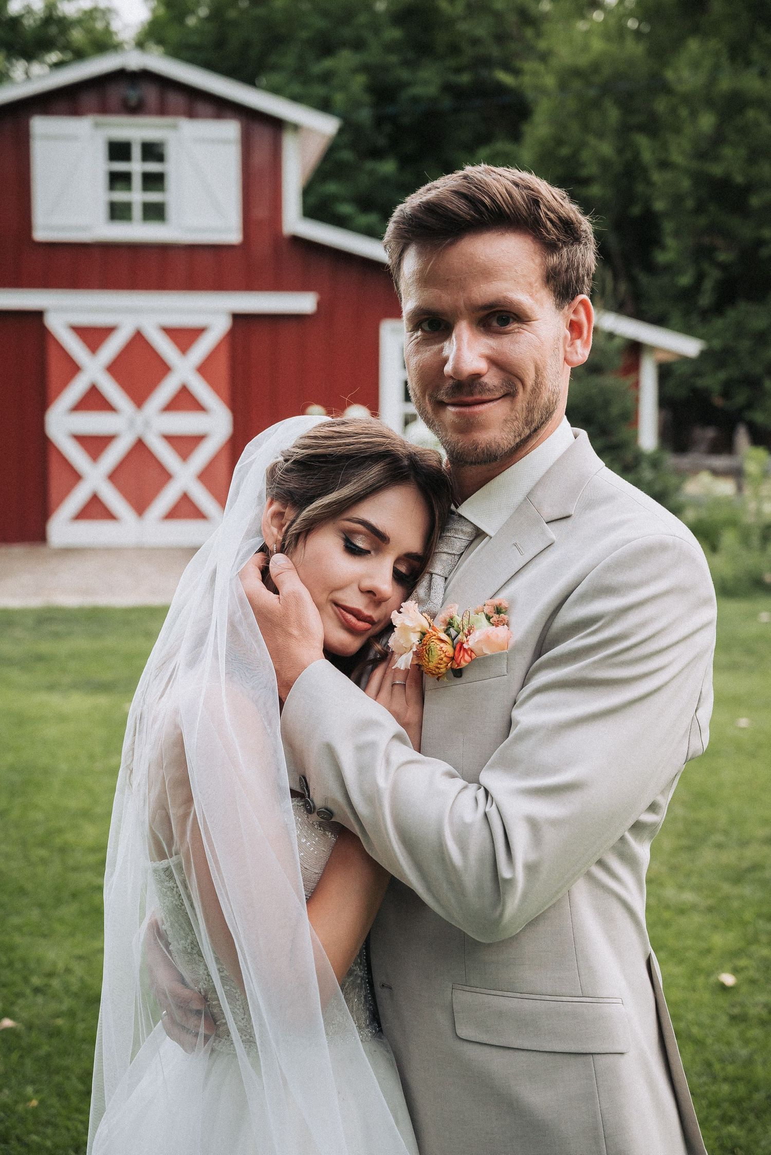 A couple shares an intimate moment during their rustic barn wedding on a sunny summer day.