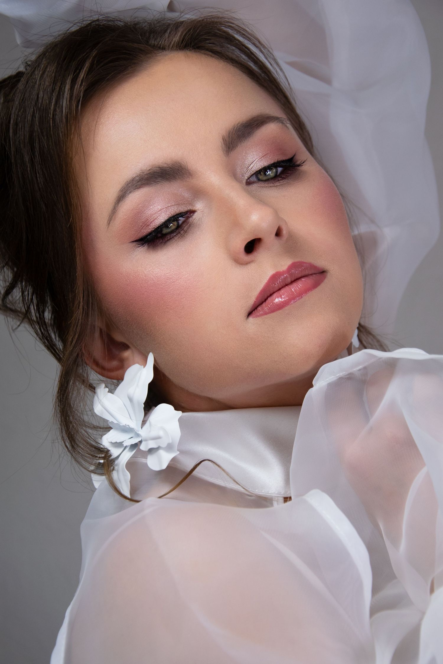 Glamorous beauty portrait with dramatic makeup, pink lips and white collar against light background.