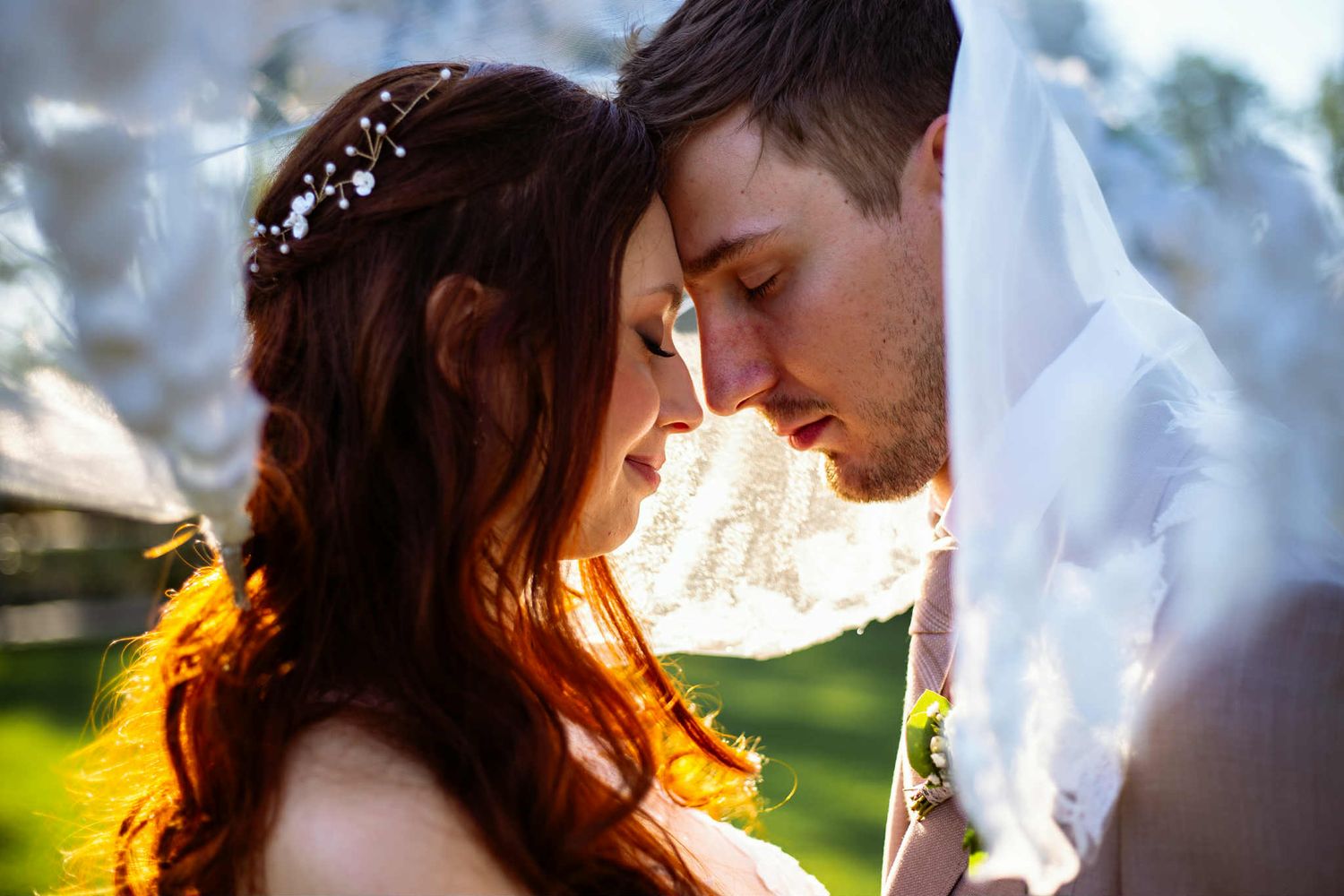 Silhouetted couple shares romantic moment during sunset outdoor photo session with soft warm backlighting.