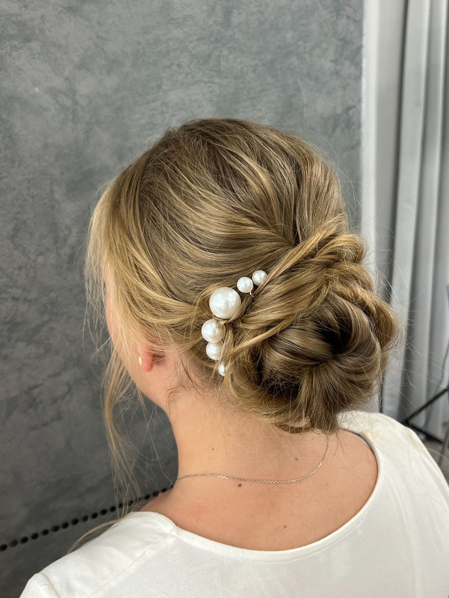 Elegant bridal updo adorned with pearl hair accessories in blonde hair.