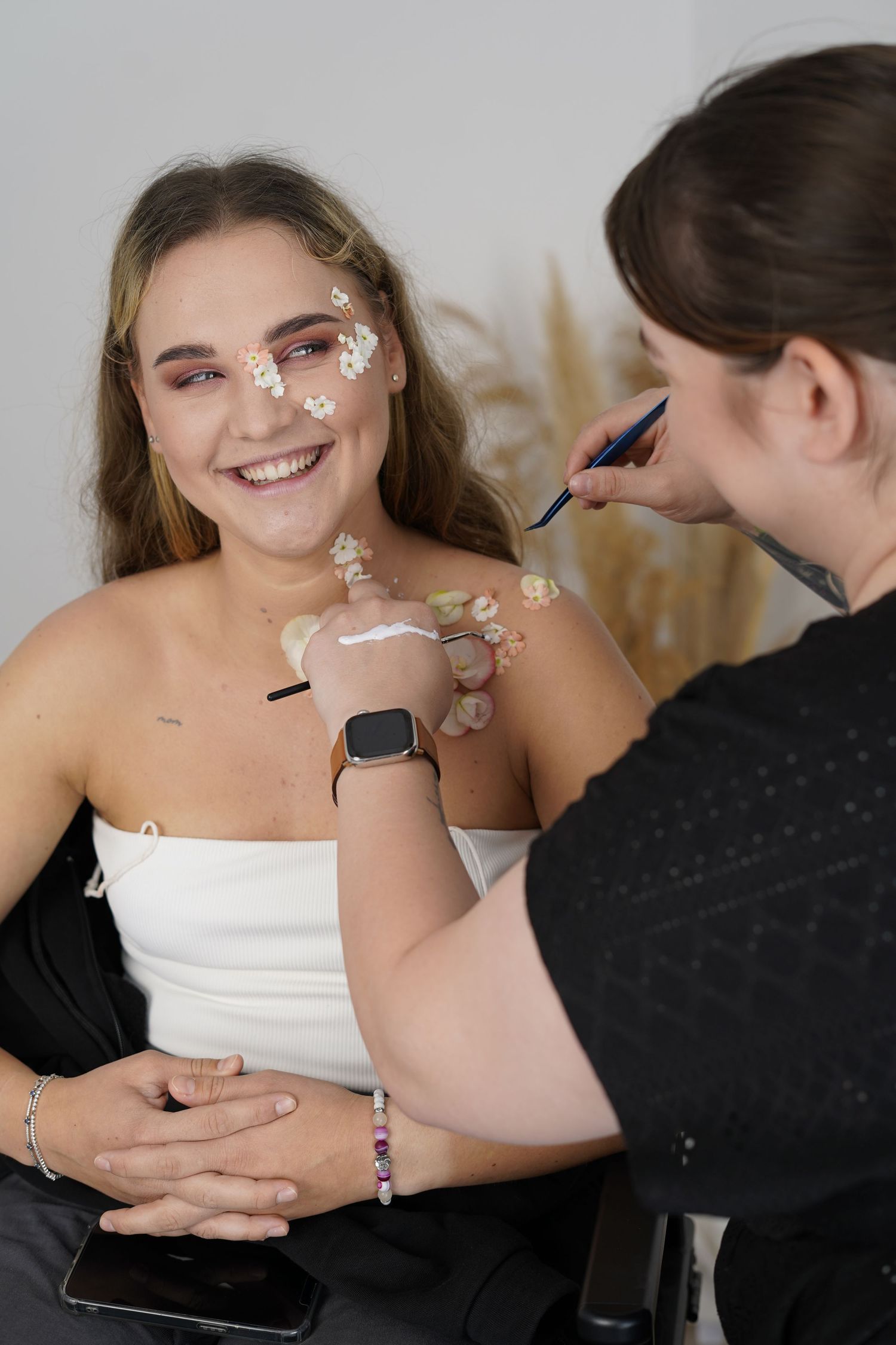 Makeup artist applying decorative flowery designs on client.