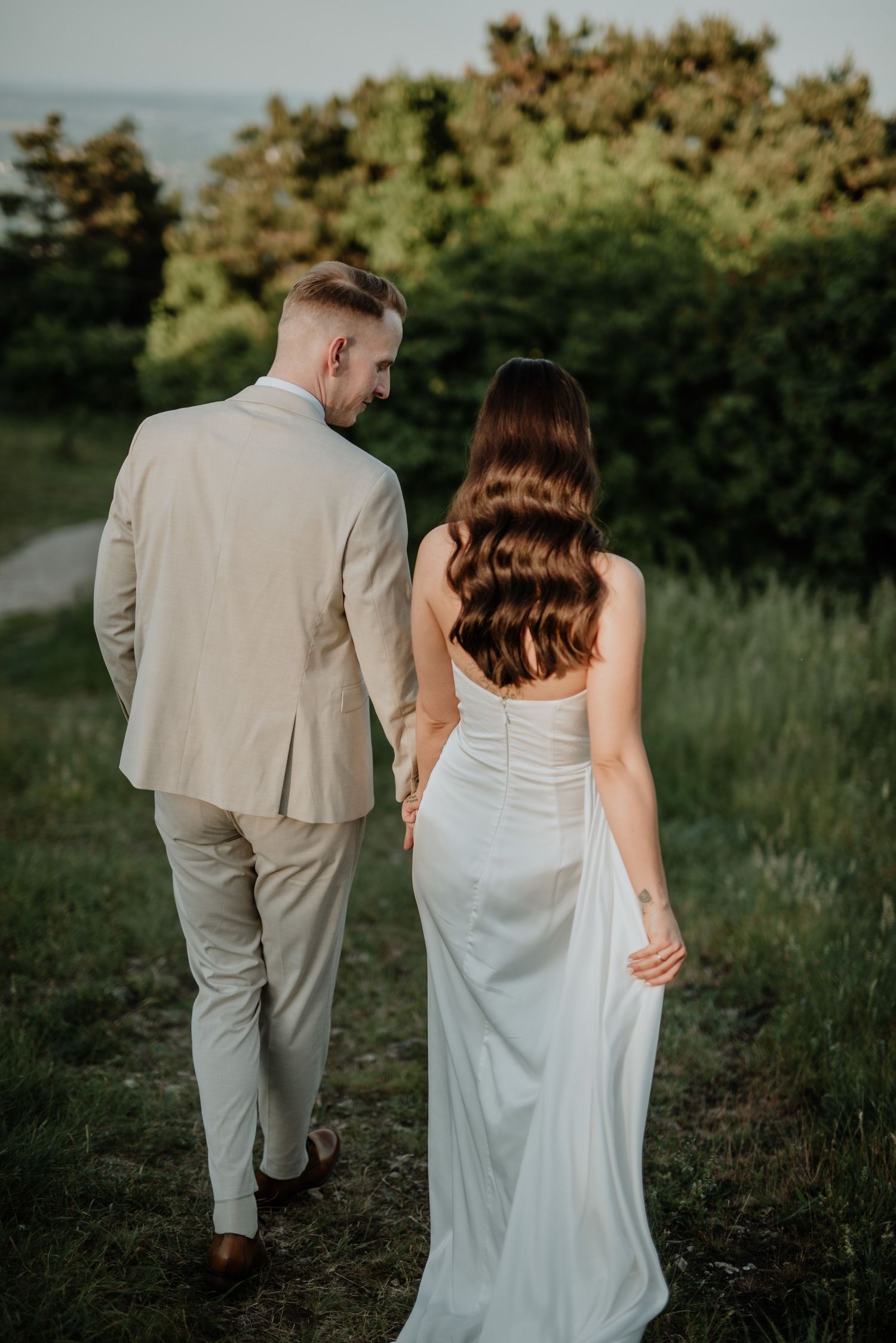 A couple in bridal attire walking through a sun-lit meadow at dusk captured in multiple artistic wedding photo angles.