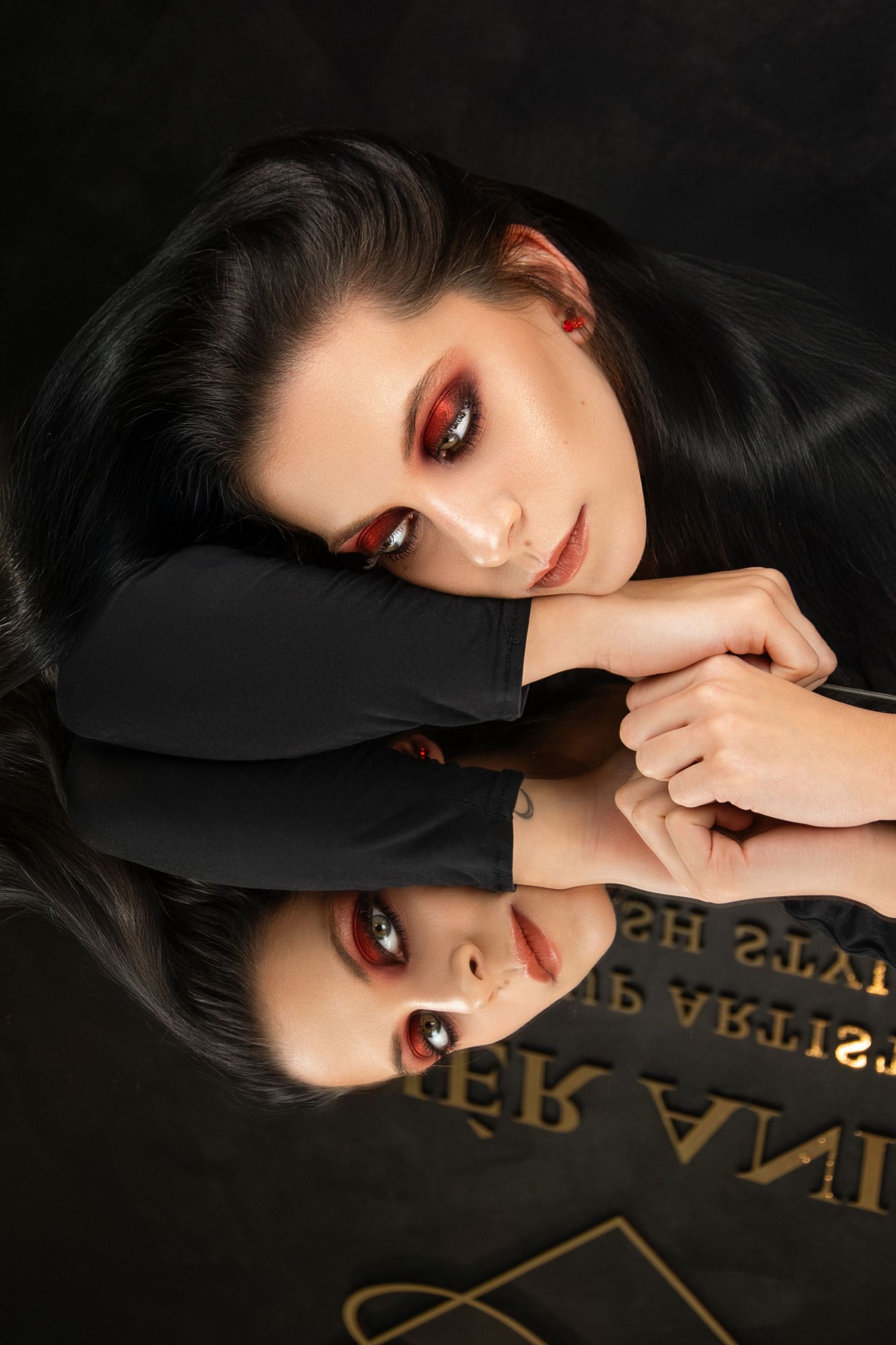Artistic beauty photo with dramatic red eye makeup reflected in mirror surface.