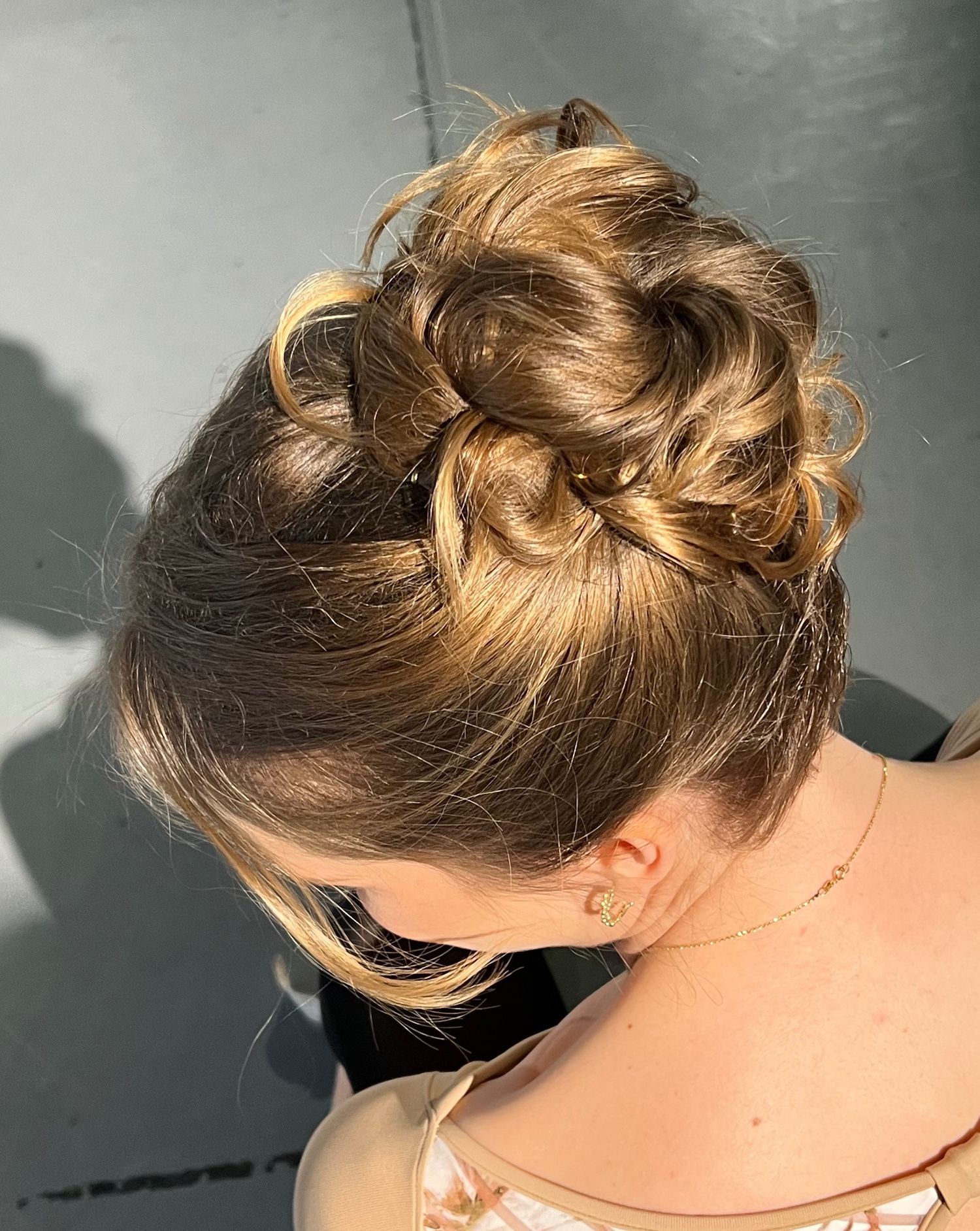 Messy bun updo hairstyle with textured layers and blonde highlights.