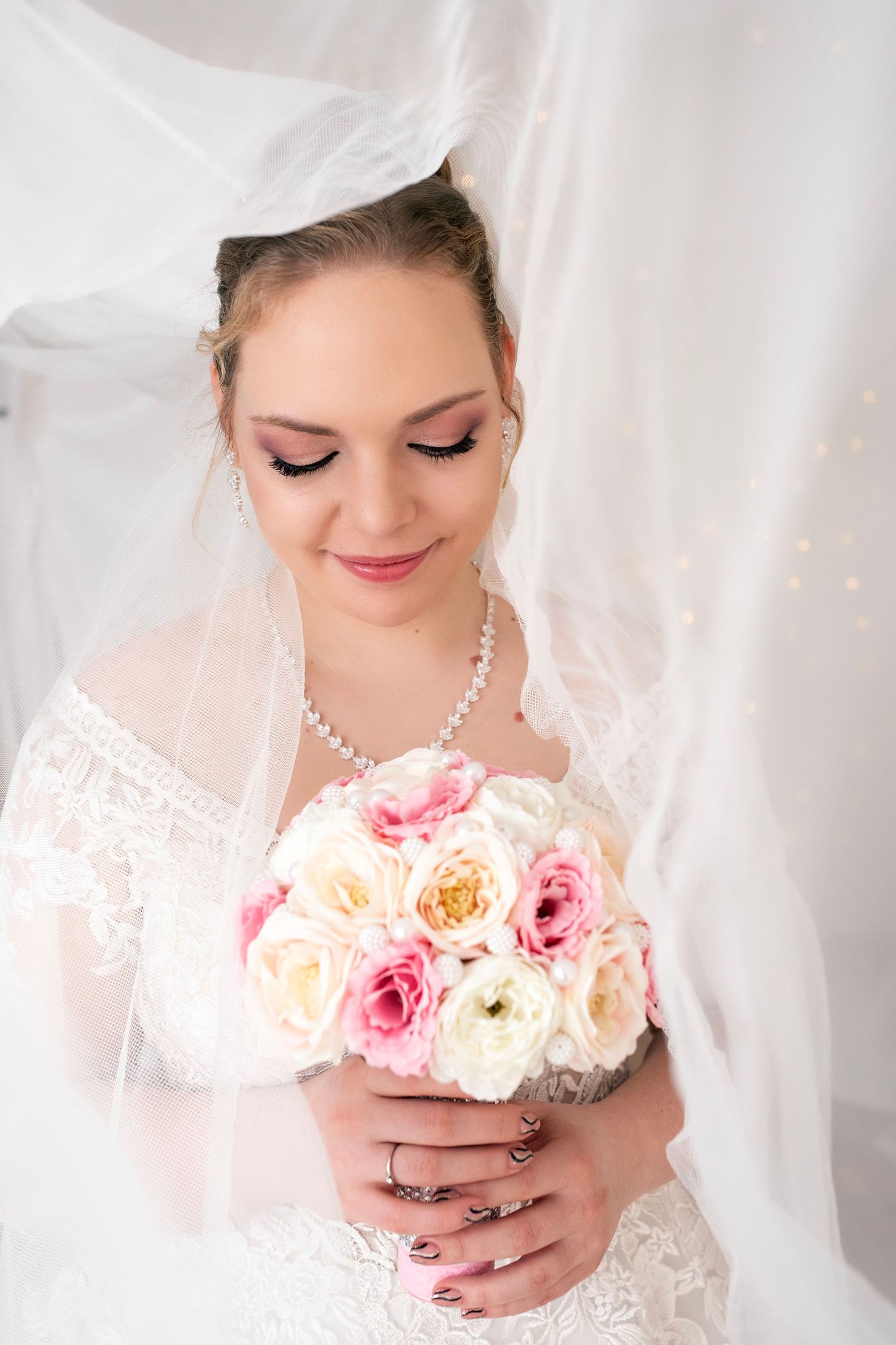 Romantic bridal portrait with pearl necklace holding pink and white roses.