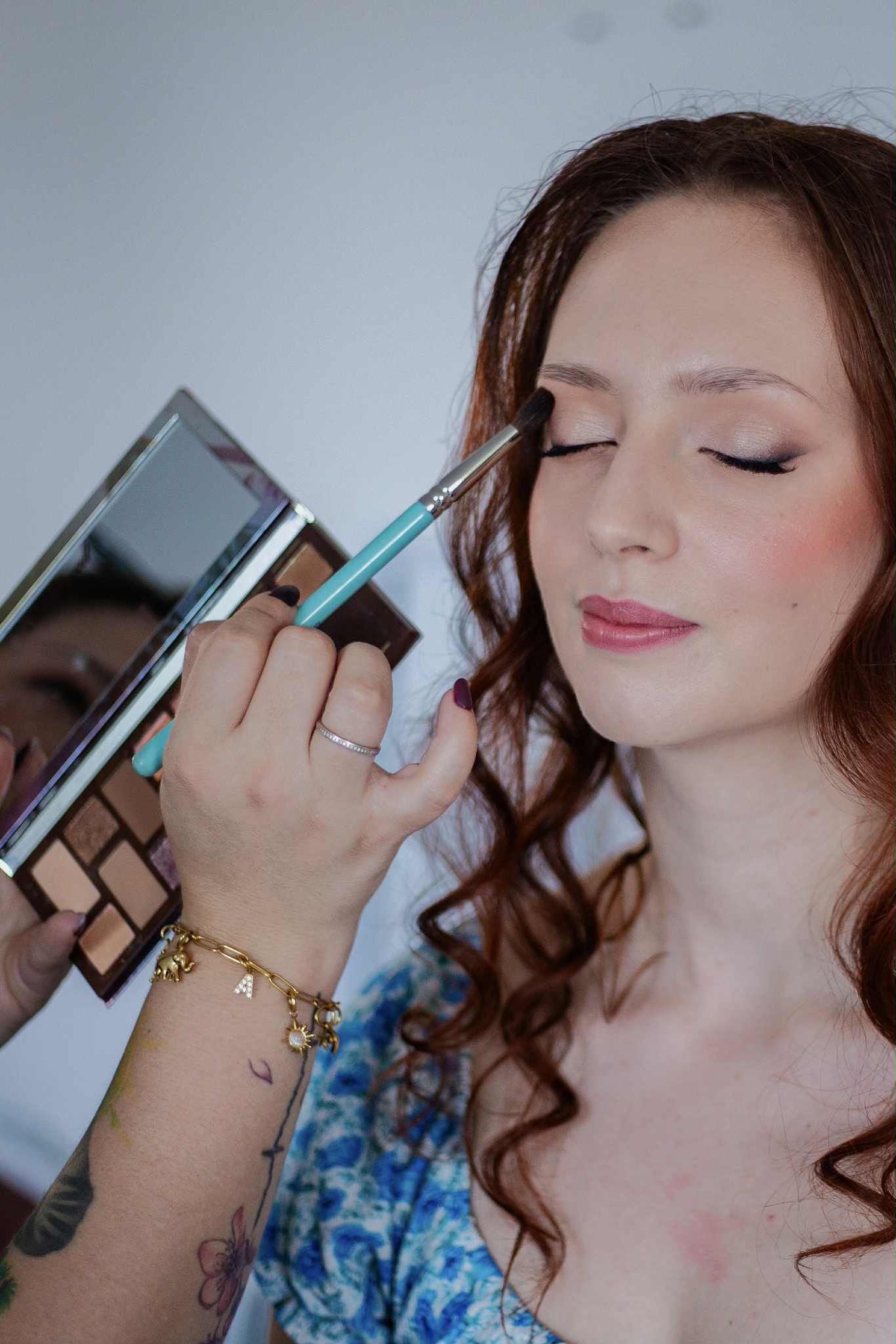 A makeup application process showing eyeshadow being applied with a blue and white floral pattern visible in each frame.