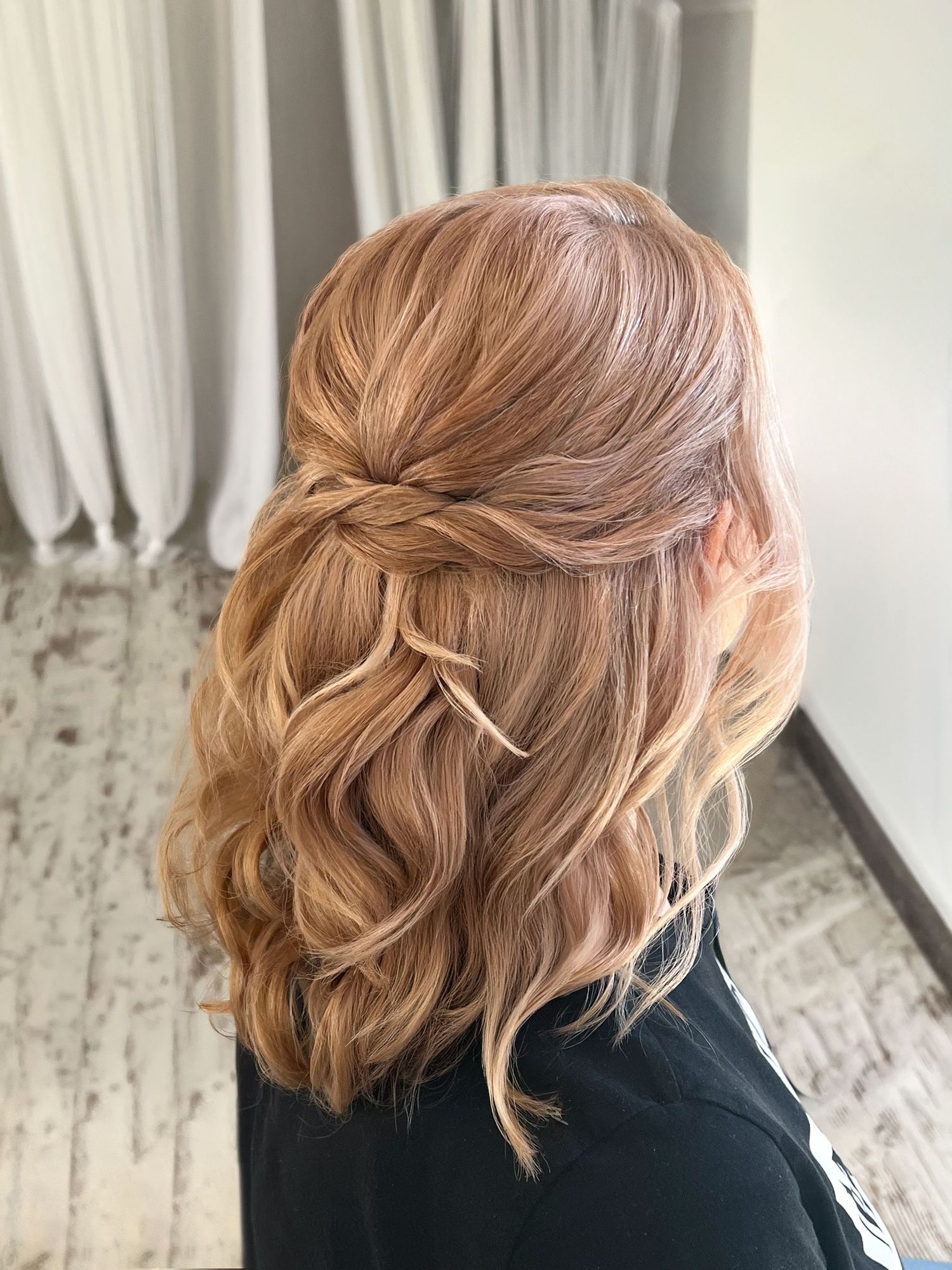 Half-up half-down hairstyle with soft golden blonde waves and twisted back detail, perfect for weddings or formal events.