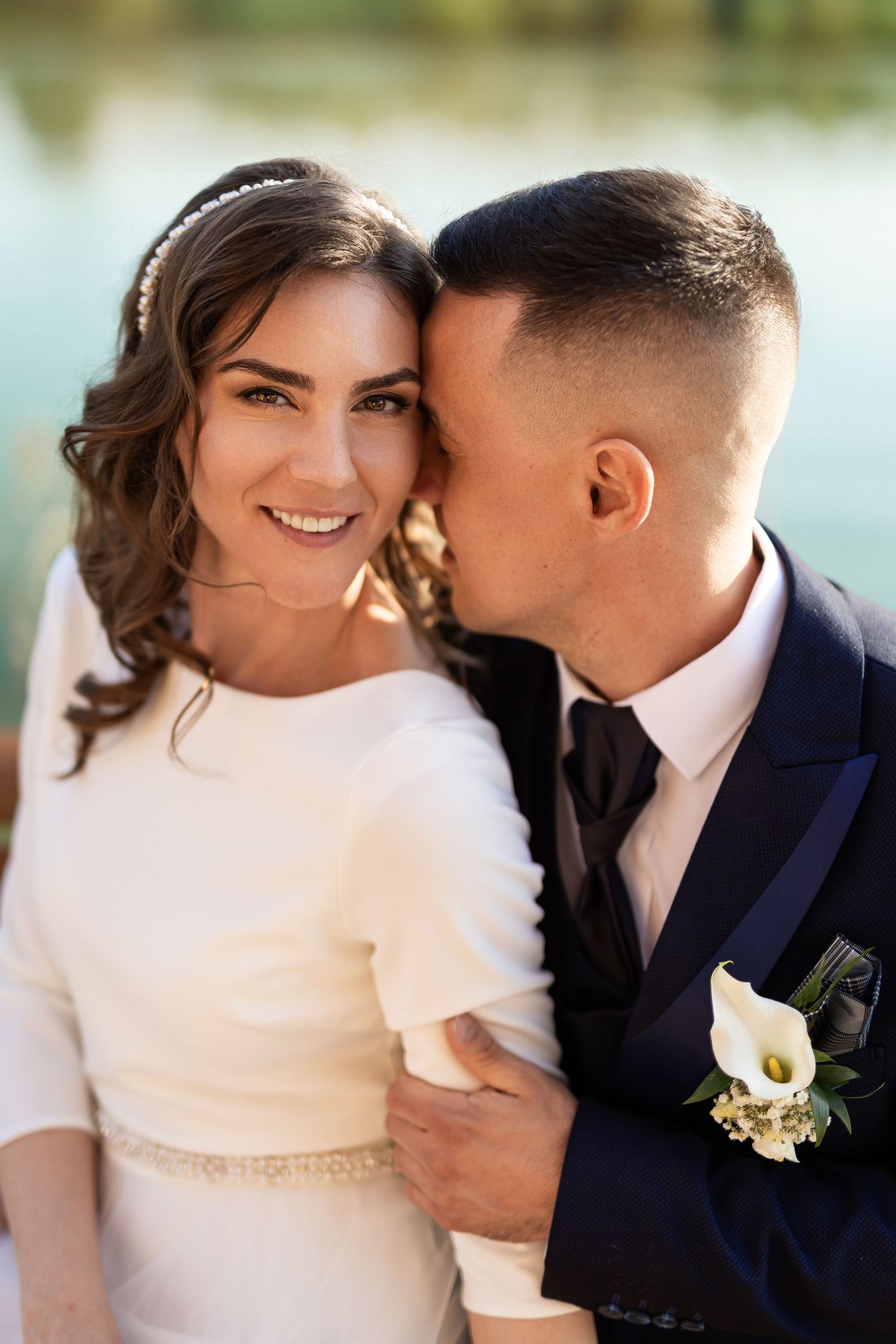 A wedding couple embraces intimately in a dreamy outdoor setting with soft natural light.